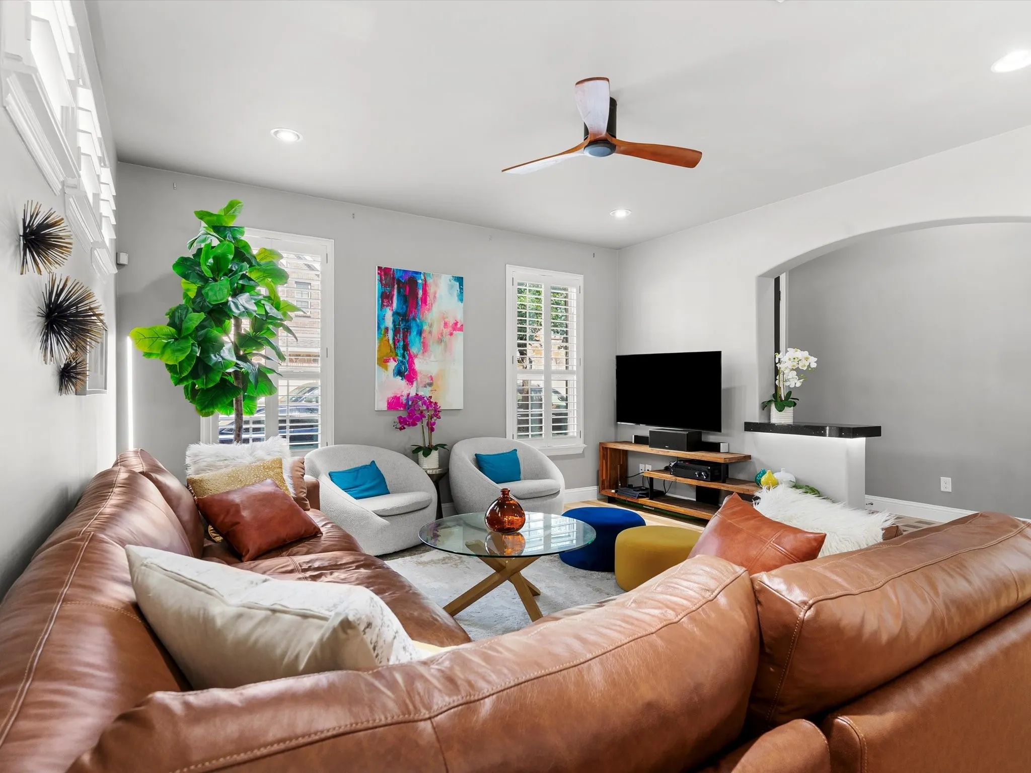 Living area featuring recessed lighting, a ceiling fan, window shutters, and an archway