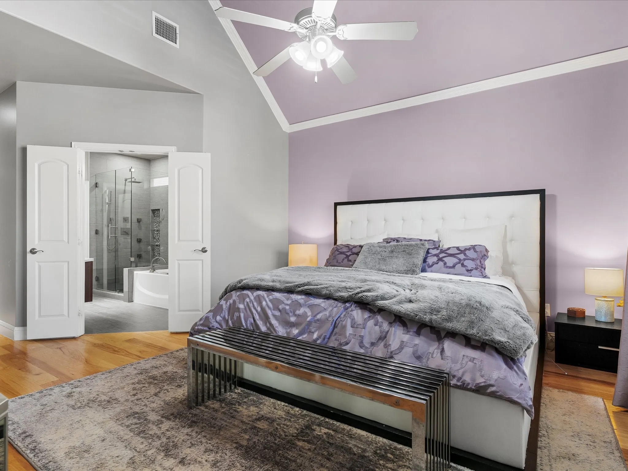 Hardwood flooring throughout the room with an angled ceiling and a ceiling fan