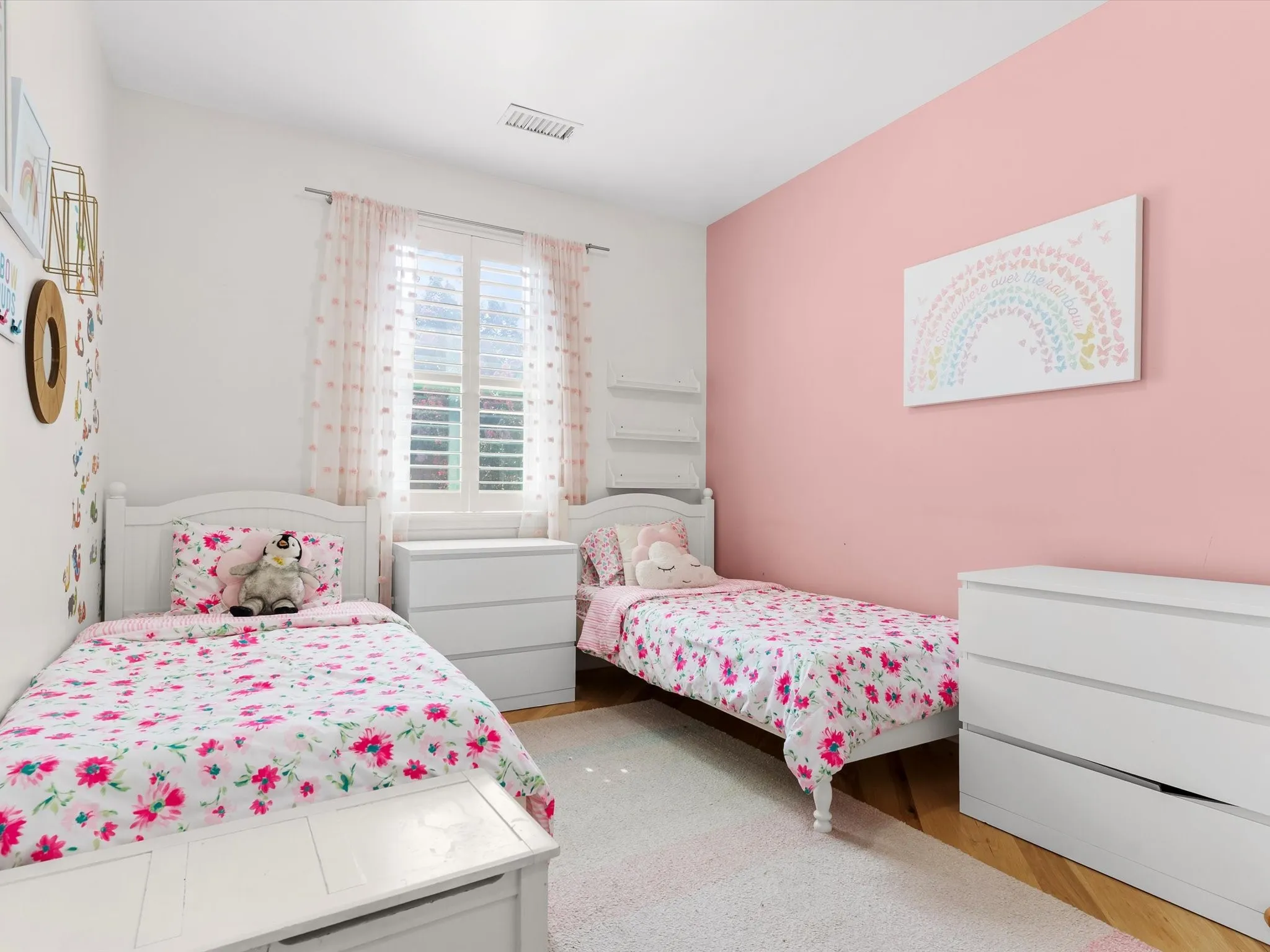 Bright room featuring a single window with plantation shutters, white wood-finish trim, a recessed ceiling vent, and wood-finish flooring