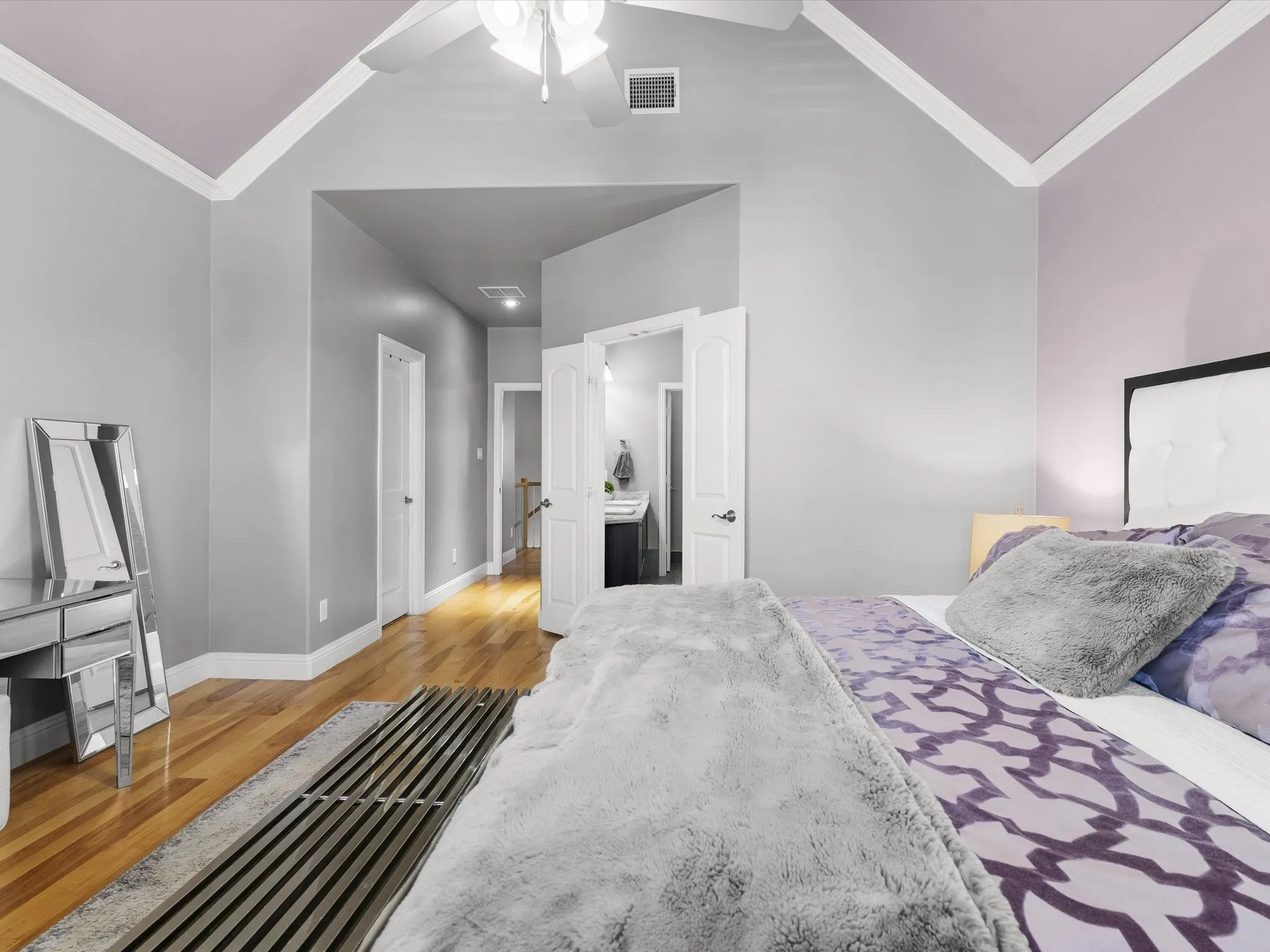 Vaulted ceilings with crown molding and a ceiling fan, hardwood flooring, and a white paneled door