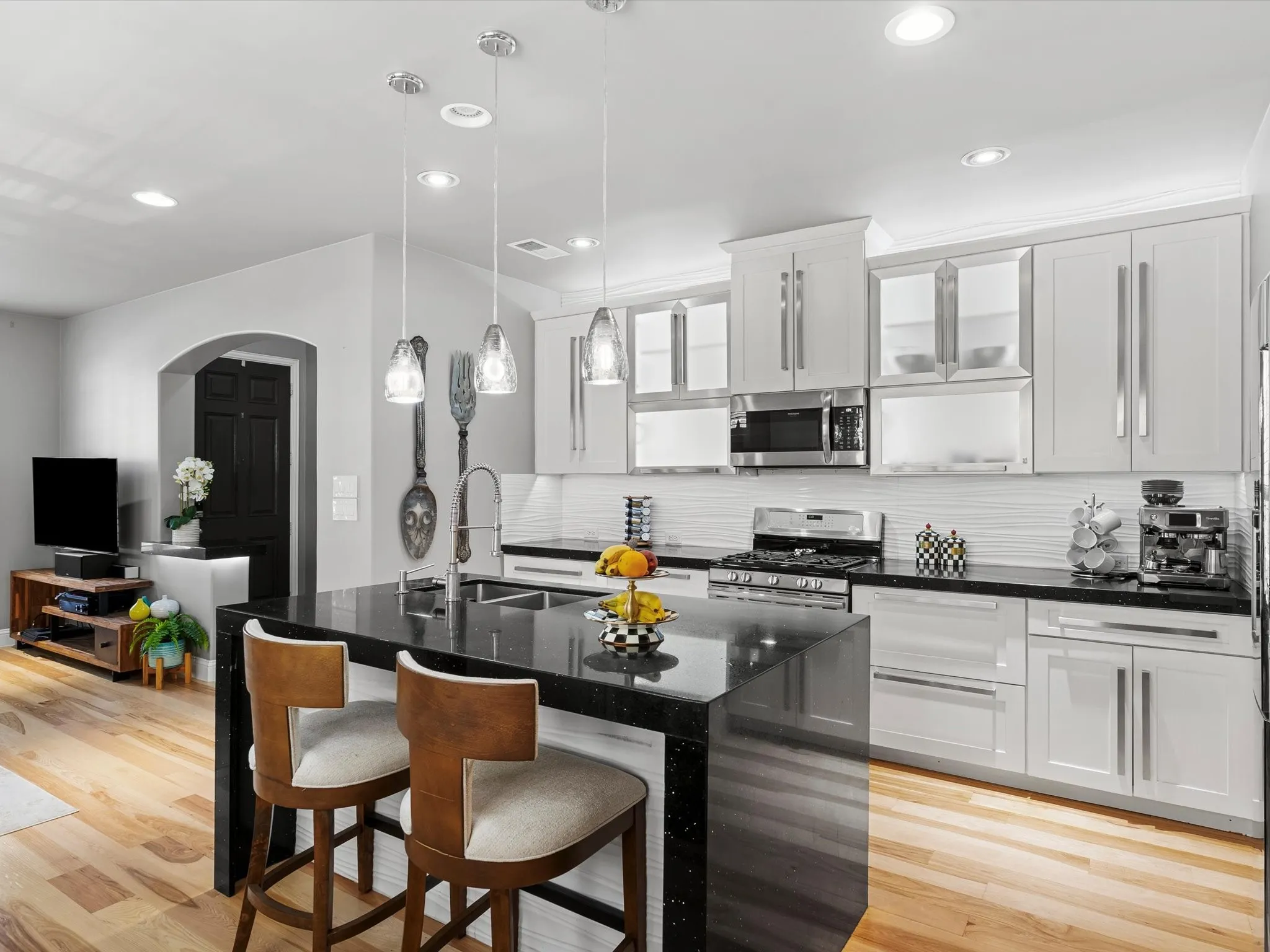 Modern kitchen featuring a black speckled countertop island with a double basin stainless steel sink and gooseneck faucet