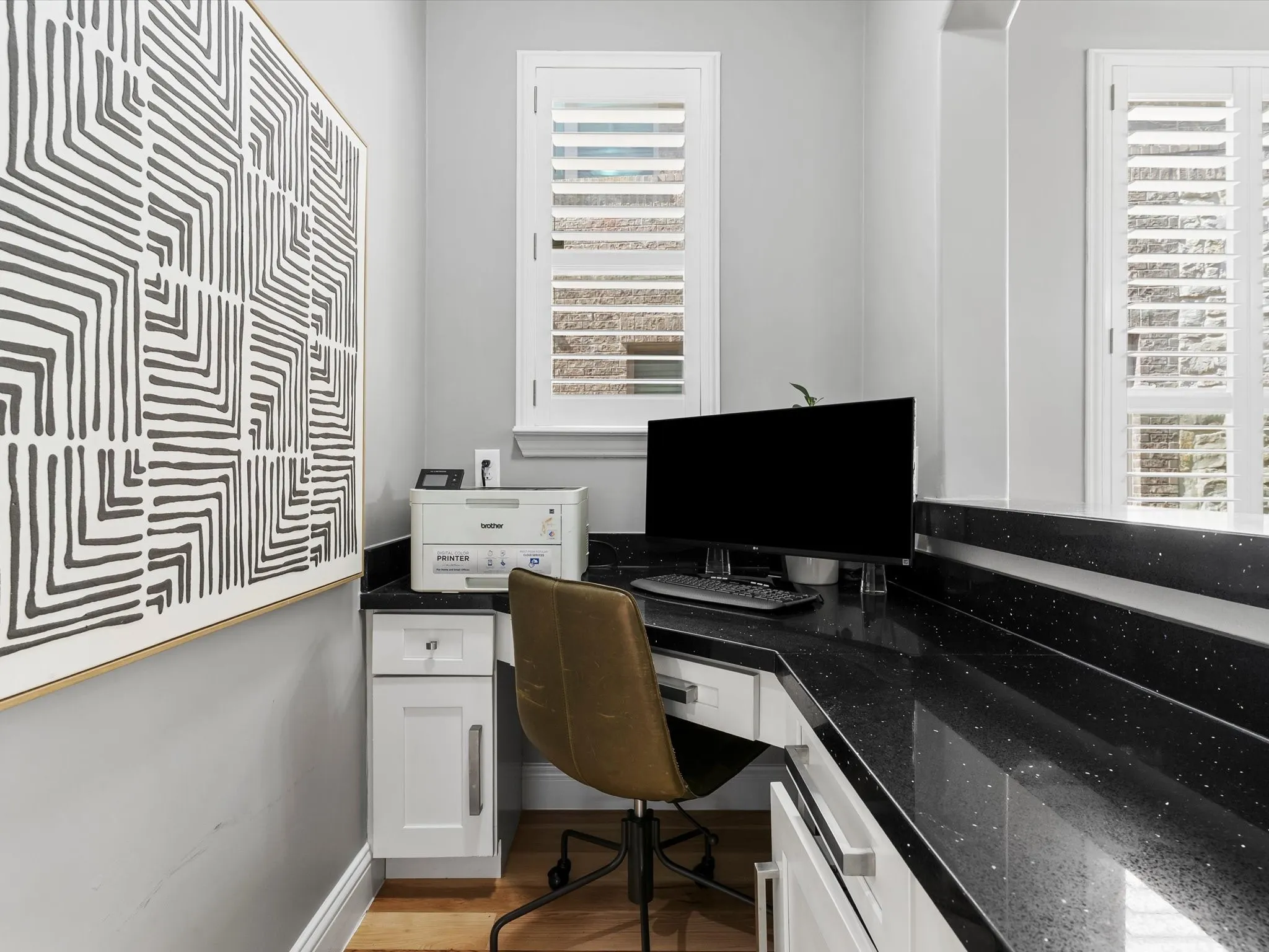 Dedicated workspace featuring built-in cabinetry, dark speckled countertops, and wood-finish flooring