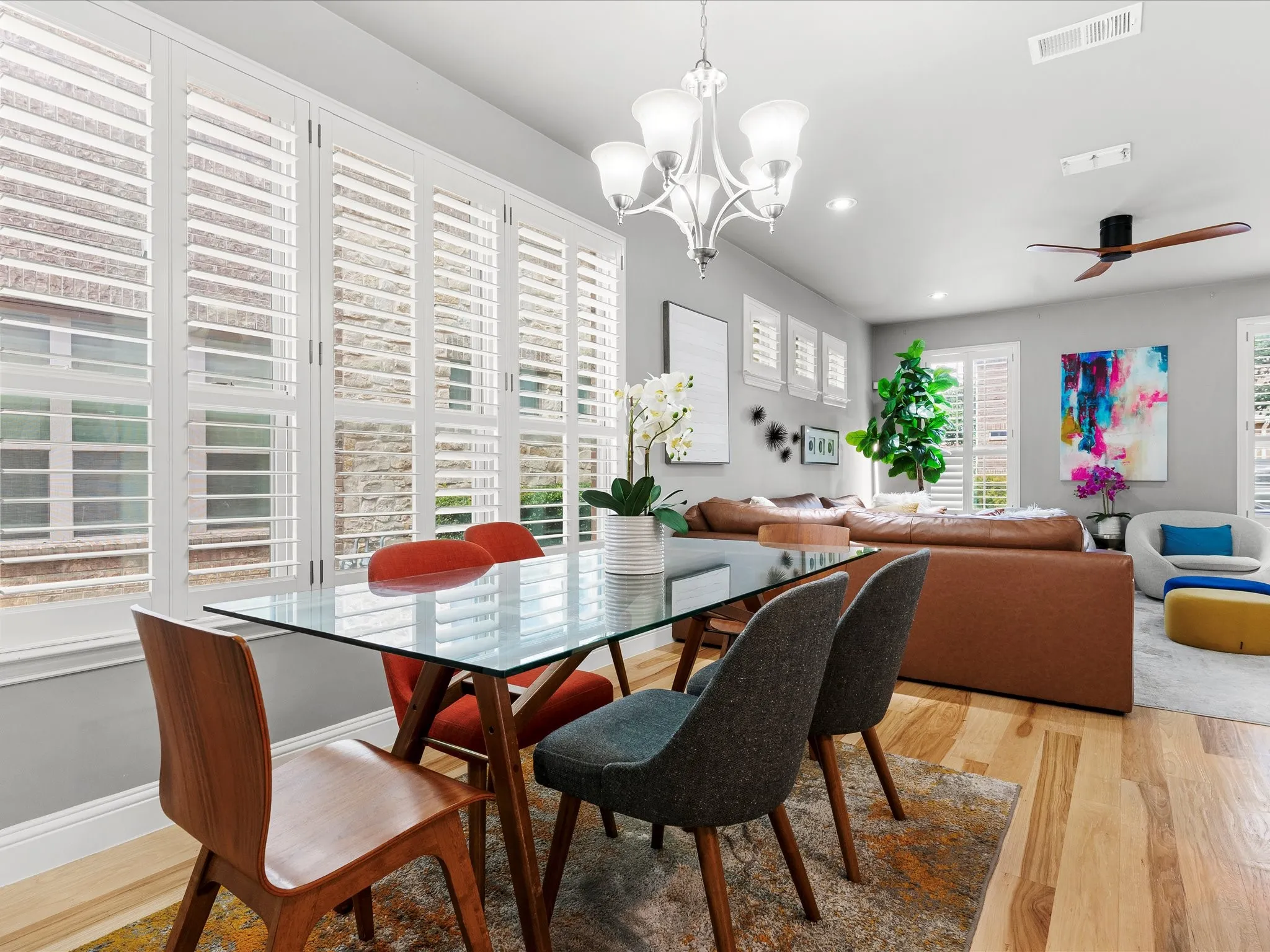 Open-concept living area featuring extensive window treatments, recessed lighting, wood-finish flooring, a contemporary chandelier, and a ceiling fan
