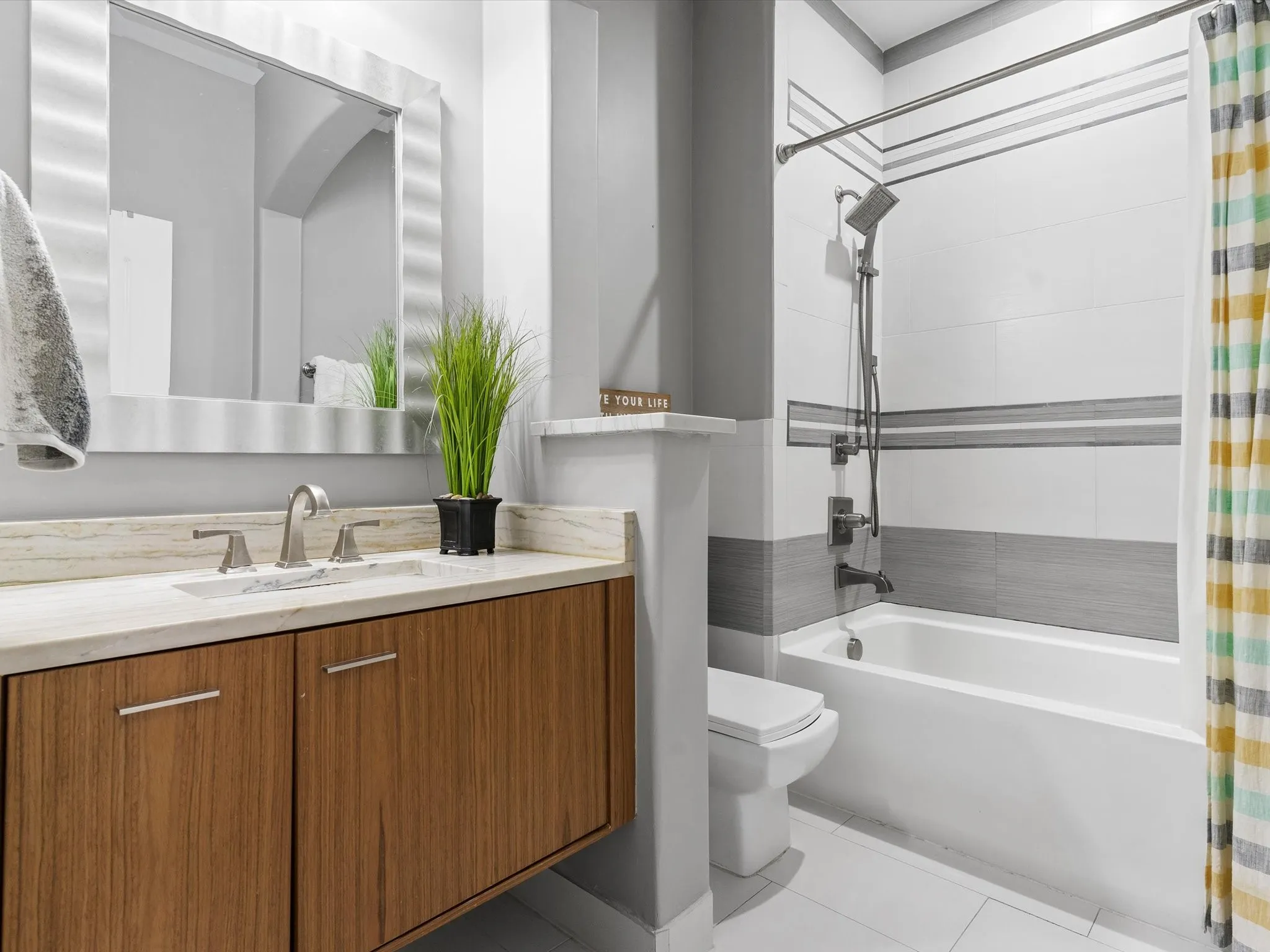 Contemporary bathroom featuring a floating wood-finish vanity with a light-toned countertop, an undermount sink, and brushed nickel fixtures