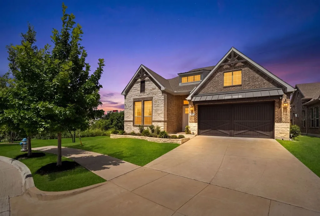 Brick and stone facade featuring a two-car garage with carriage-style doors