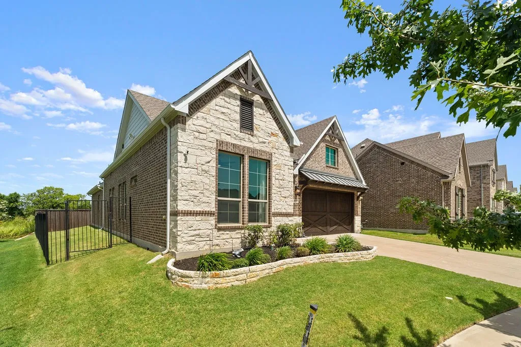 Brick and stone exterior featuring an attached garage with a wood-finish door