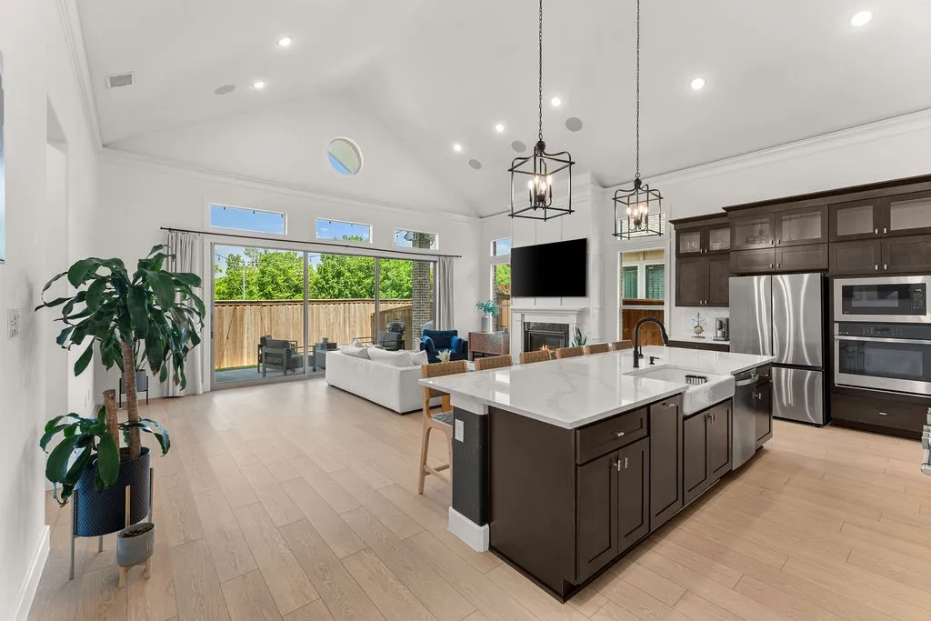 Vaulted ceiling living area featuring wood-finish flooring, a contemporary fireplace, and sliding glass doors opening to a fenced patio