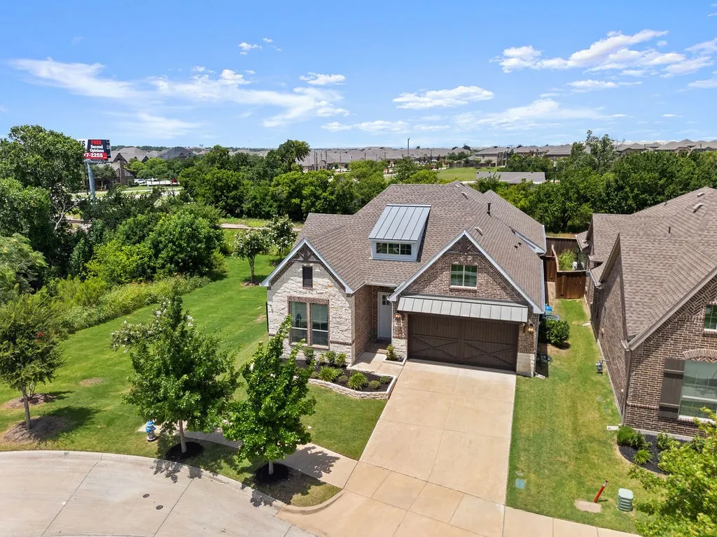 Contemporary residence featuring a brick and stone exterior with a prominent brown roof