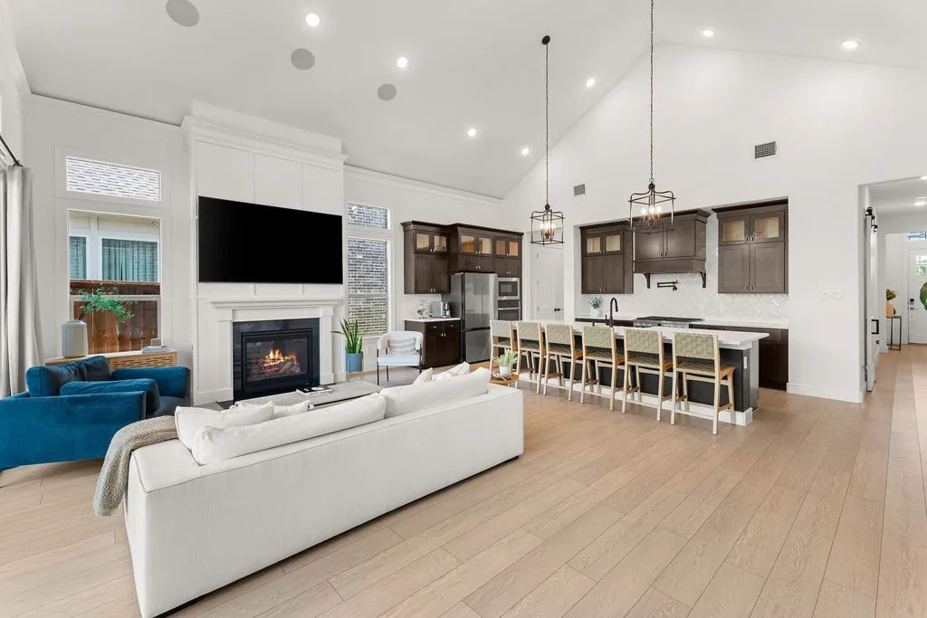 Open-concept living space featuring vaulted ceilings, wood-finish flooring, and recessed lighting