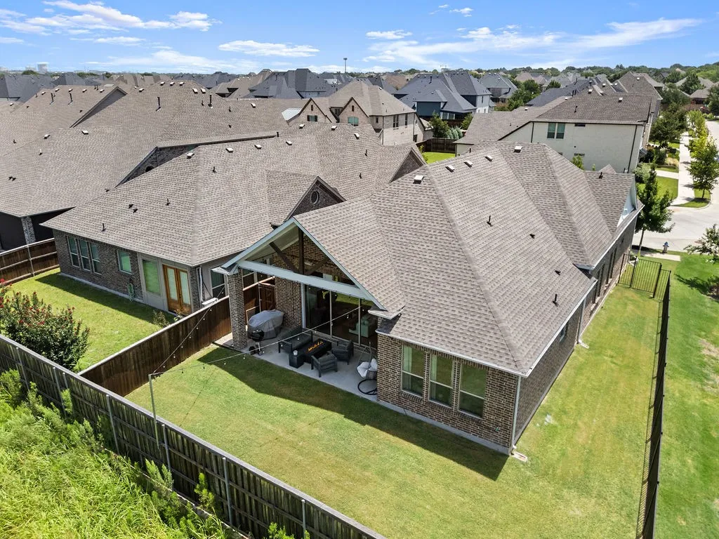 Brick exterior home featuring a covered patio, fenced backyard, and a manicured lawn