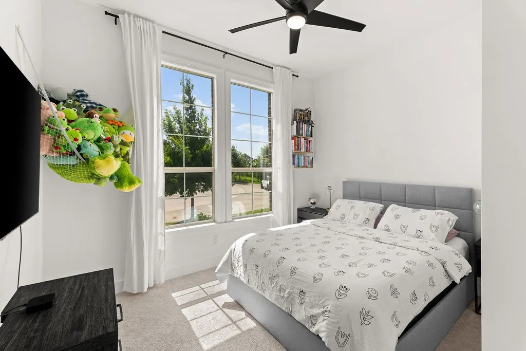 Light-filled room featuring large double windows, a ceiling fan with integrated lighting, and neutral wall tones