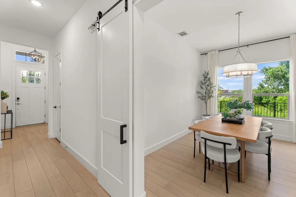 Bright dining area featuring a large window, a modern chandelier, and light wood-finish flooring