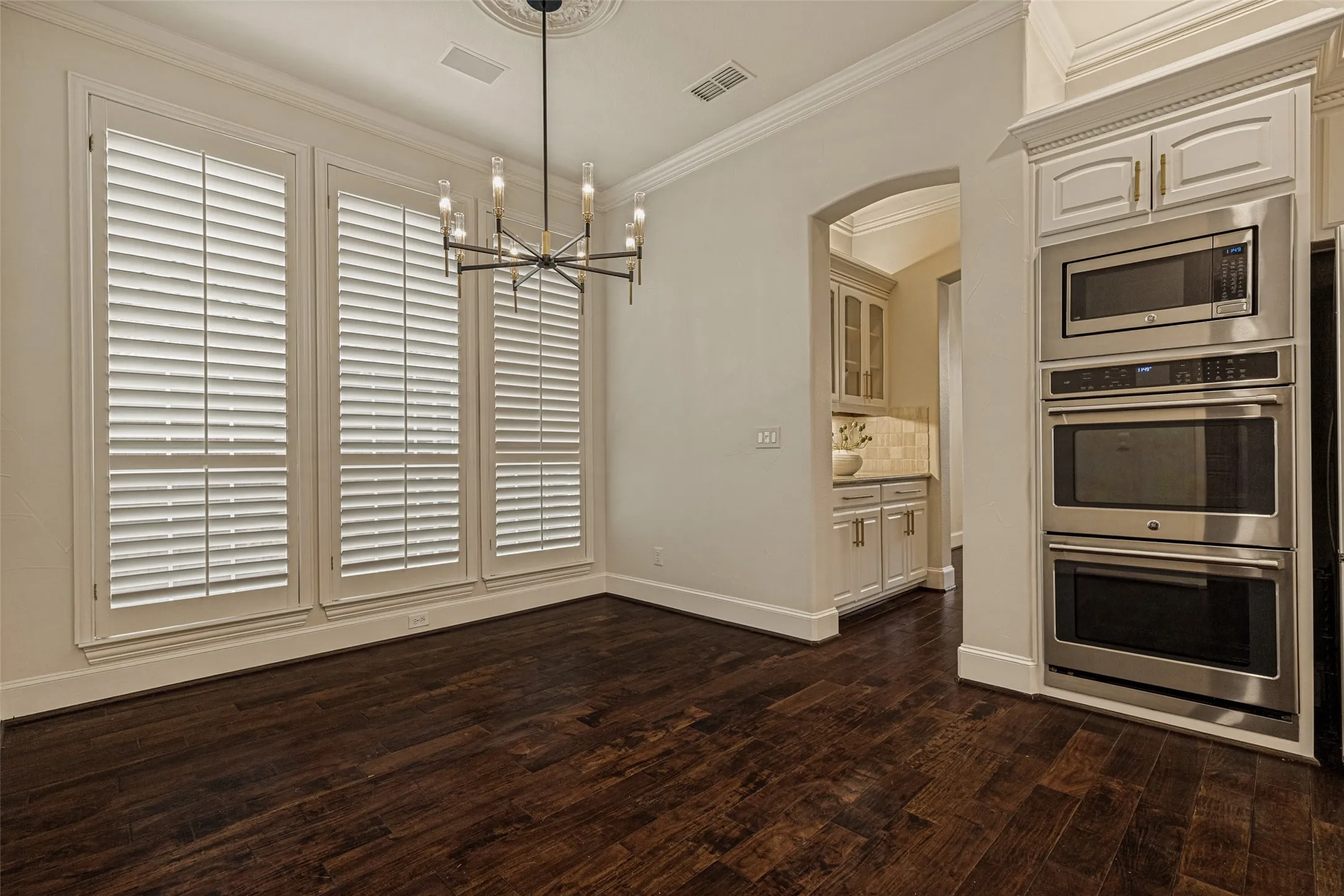 Wood flooring continues into the breakfast nook.  Crown molding embellishes the ceiling and a striking chandelier hangs from a decorative medallion at the top.  It's easy to see the tall base molding that runs through the downstairs of the home.