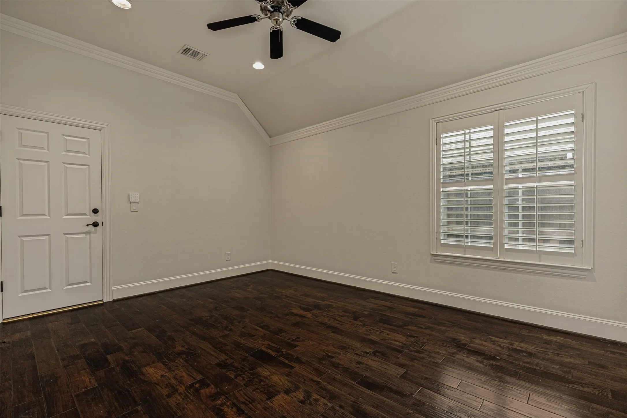 The bonus room was created by using space designed as a tandem bay of the garage.  As such, access to the garage from the home is through the room.  There is crown molding and wood floors, recessed lights and a ceiling fan in the raised ceiling - all in keeping with the upscale amenities and decor throughout the home.  A pair of windows has shutters.