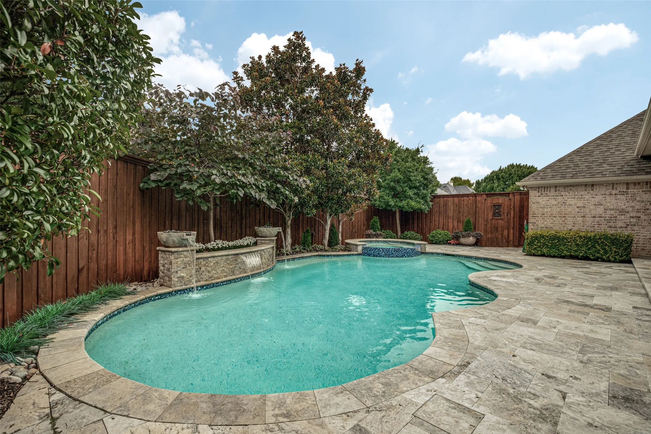 An attractive board on board fence encloses the pool.  The pool was updated and remodeled in 2020.  Water spills into the pool from two vessels and a center spot in the stacked stone planter feature.  The pool surface is light-toned Pebble Tec glass bead plaster that provides an aquamarine color to the pool and spa.  Glass tile was installed during the update.  Pool equipment  (pump/filter/heater/blower) were recently replaced with a new pressure cleaner pump.  And swimming in the evening is fun with LED multi-colored lighting.