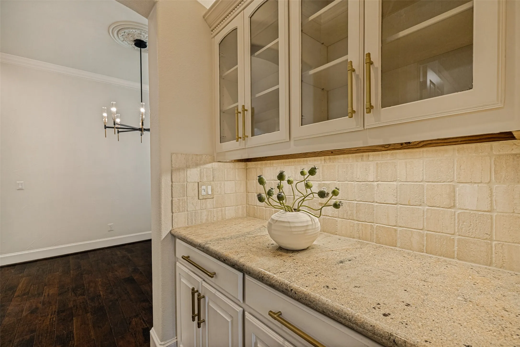 This convenient butler's pantry serves the kitchen and the dining room equally.  Cosmetically, it matches the style and decor of the kitchen, but has glass upper cabinet door fronts for display.  Wood floors and crown molding also continue into the area.  Perfect for a coffee bar or serving station, it will definitely be handy.