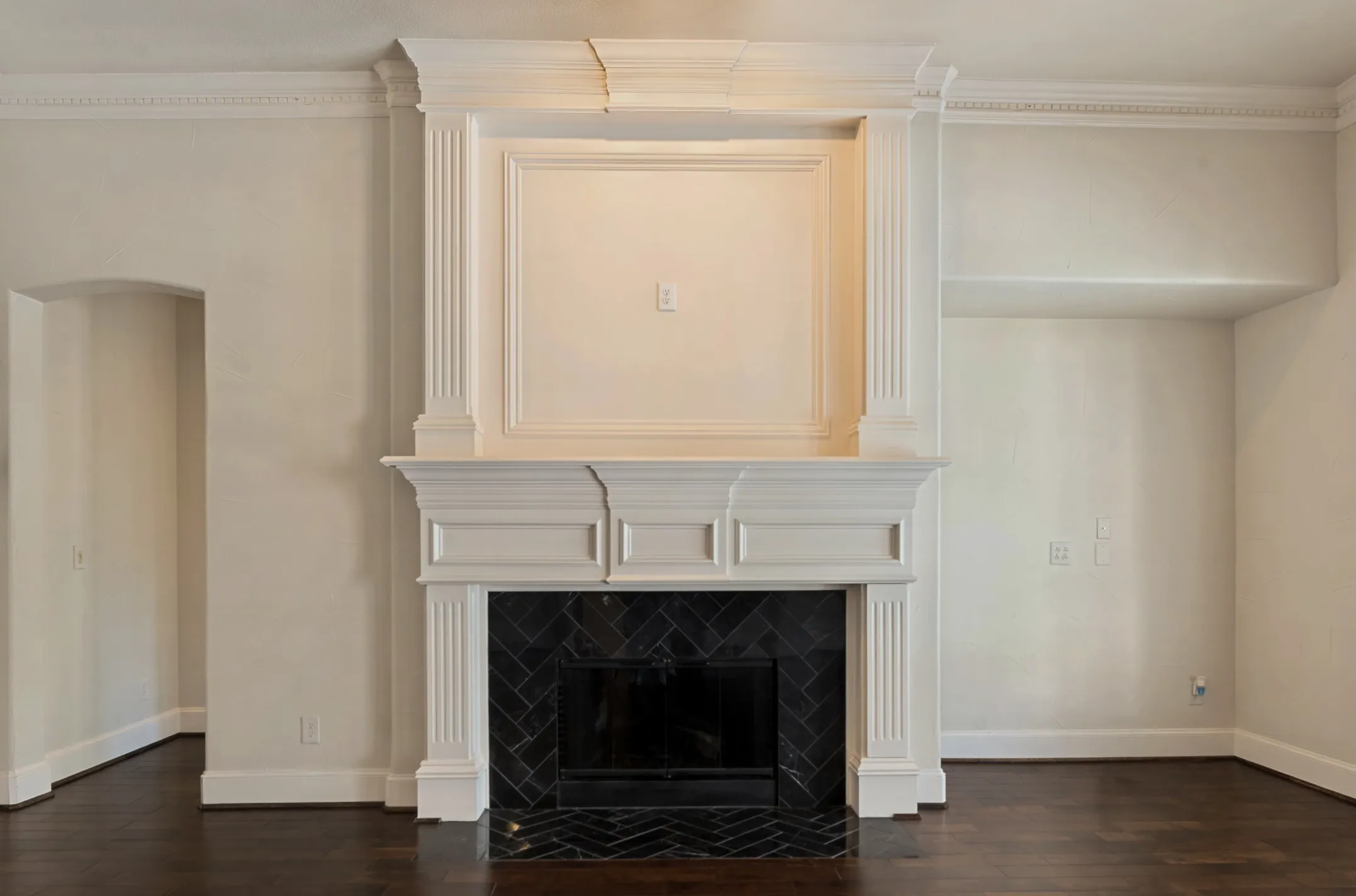 The focal point of the family room is the hallmark elegant Huntington Homes double stacked fireplace.  Extensive trim molding creates a remarkable mantle.  The updated fireplace surround is of black marble set in a herringbone design.  A niche on the right is appropriate for a piece of furniture or a TV with a console below.  A spotlight above the fireplace adds emphasis to the feature and highlights possible artwork on the upper section of the mantle.