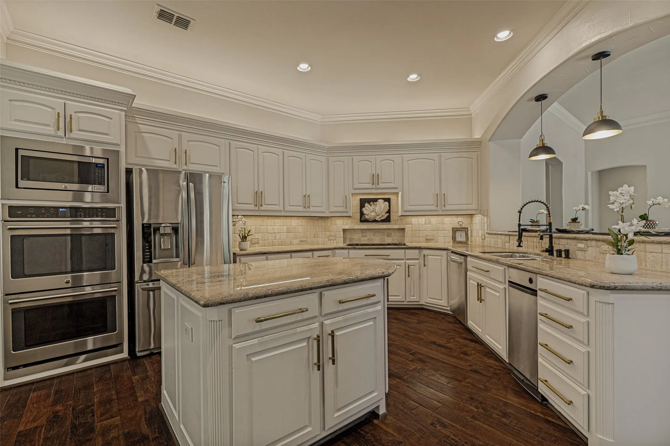 Cooks will love this beautifully appointed chef's kitchen!  Abundant white cabinets contrast well with the rich wood floors.  Pretty granite countertops and travertine backsplashes coordinate nicely. Appliances include updated GE Cafe double ovens and microwave.  A Dacor downdraft cooktop was also recently added.  An LG dishwasher , GE Profile trash compactor and an LG refrigerator that stays with the home complete the package.  A double stainless sink is topped with an upgraded faucet.