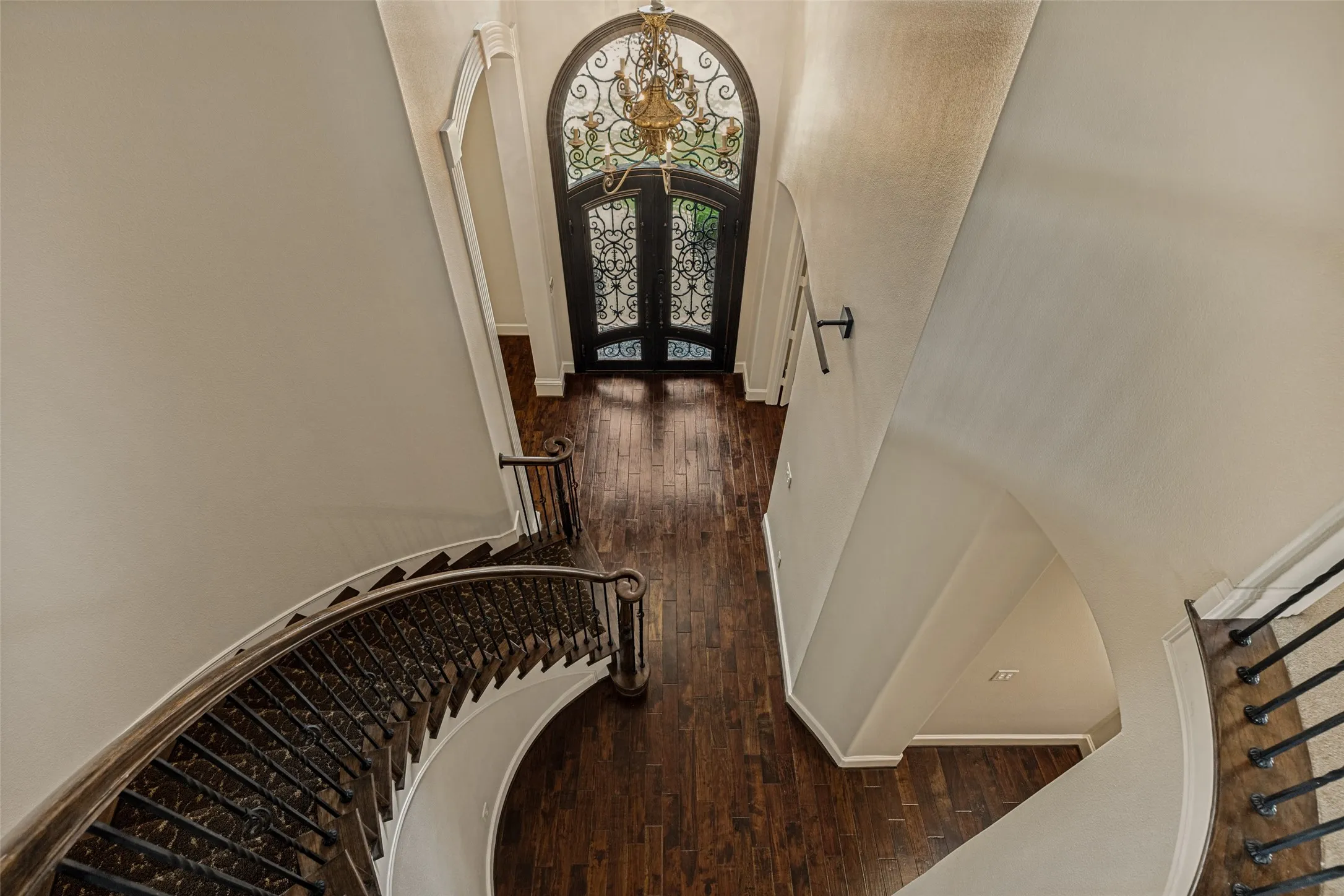 Absolutely spectacular!  The architectural design elements in this home are impressive.  The tall ceiling in the foyer shows off the column and bonnet trim work in the arched entry to the formal living and dining rooms.  The iron doors and gleaming brass chandelier also emphasize the volume in the area.