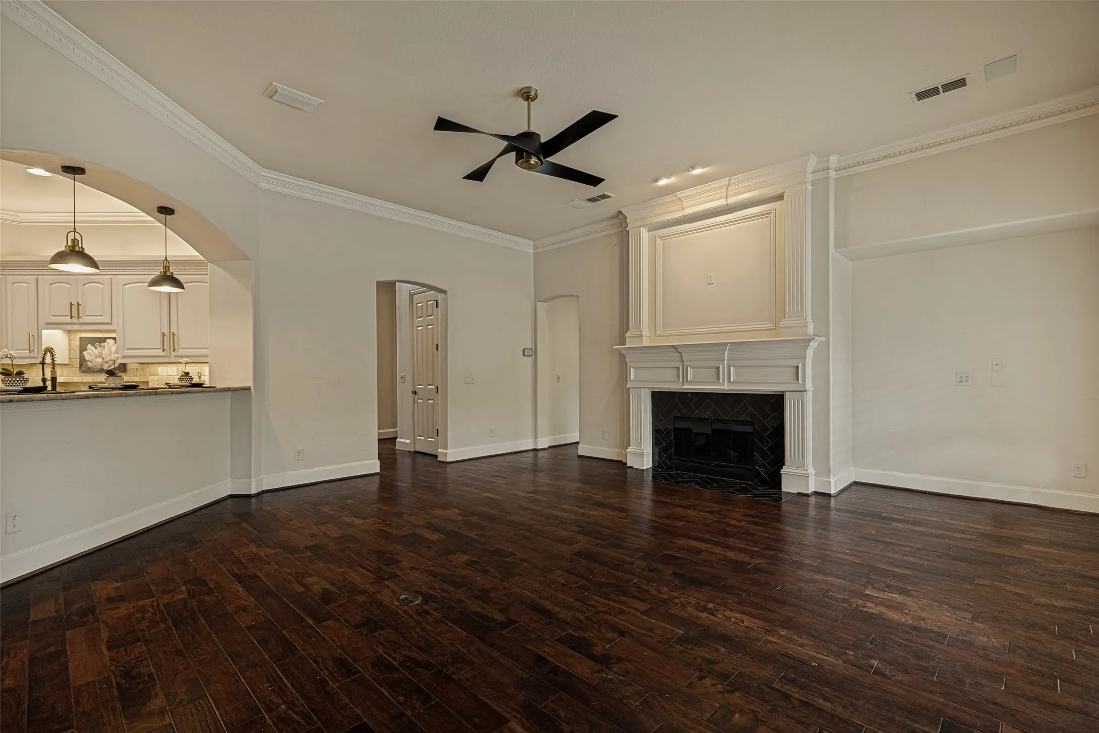The open design of the family room includes the kitchen and breakfast nook.  Crown molding with dentil ornamental trim decorates the ceiling and wood floors are below.