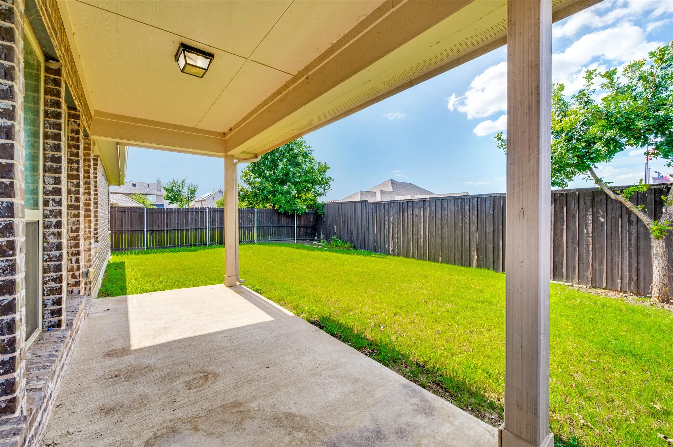 Covered concrete patio with a flush-mount outdoor ceiling light