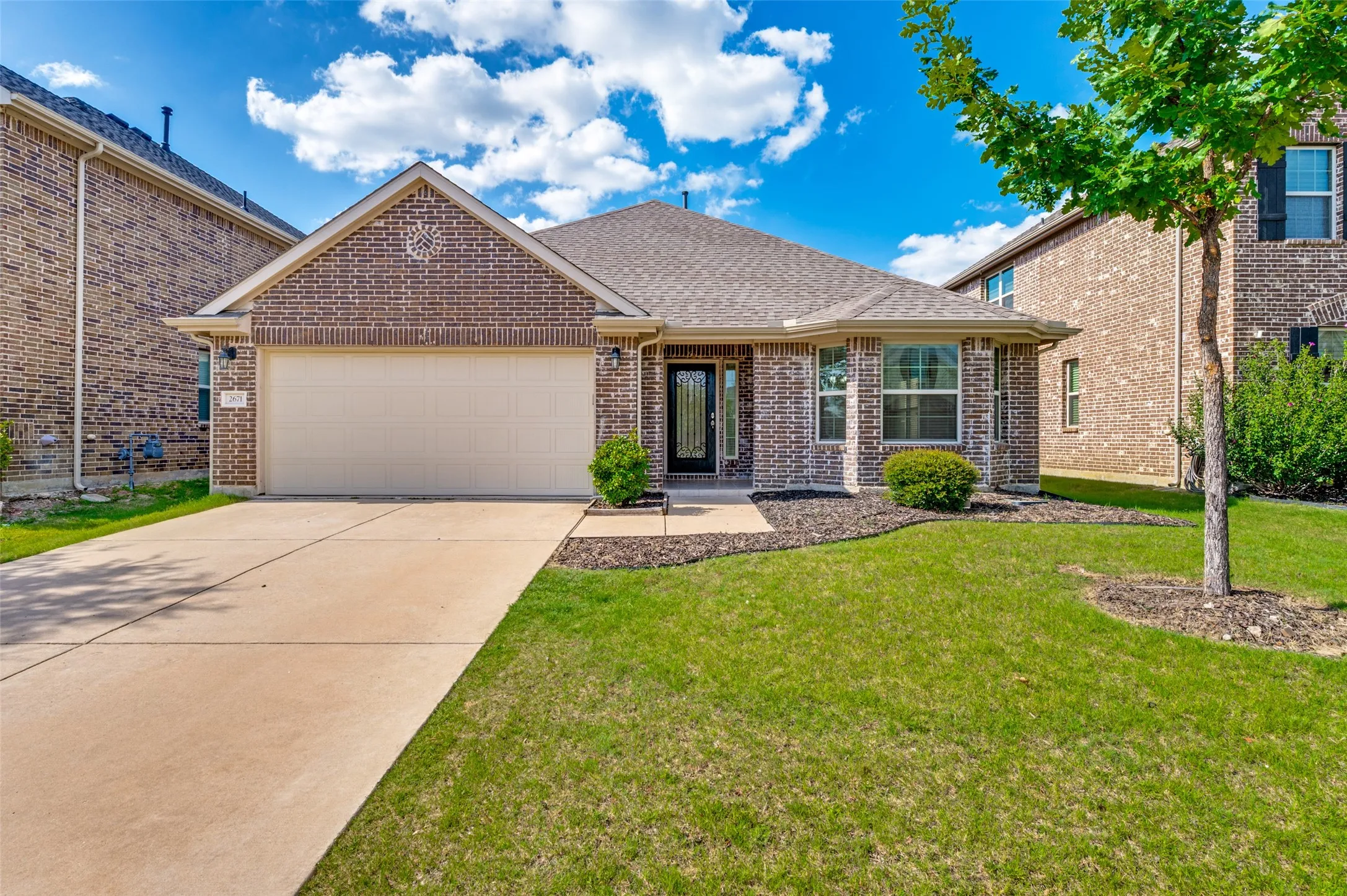 Brick exterior with an attached garage and a concrete driveway
