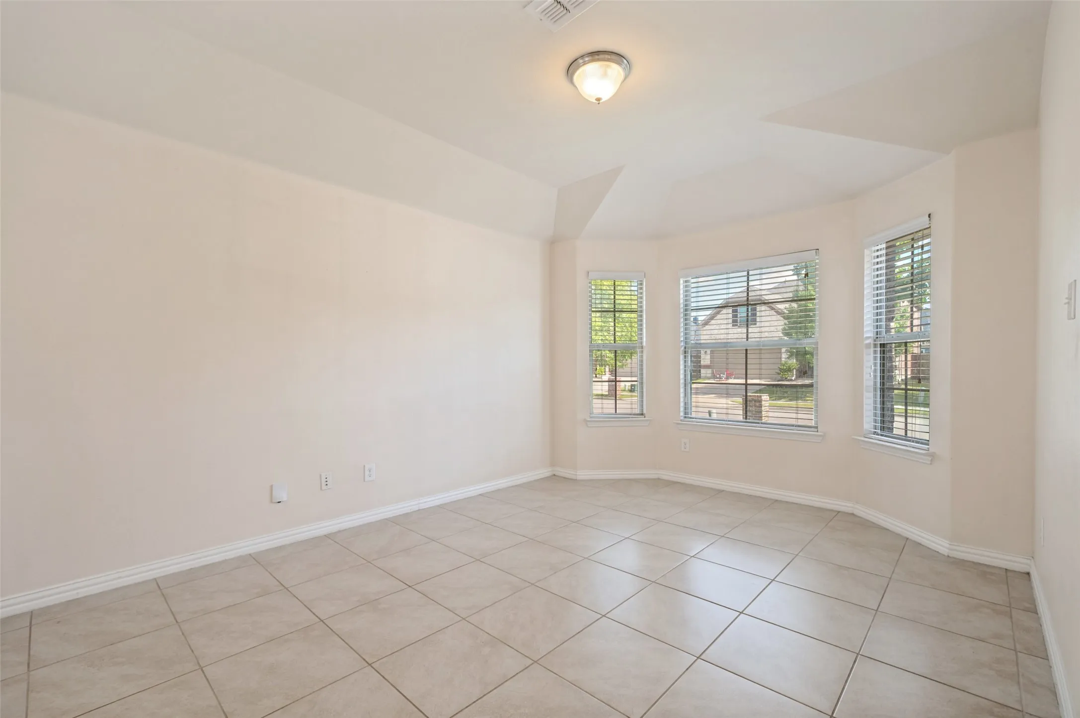 Room featuring a bay window with three individual windows, tile flooring, and a semi-flush mount ceiling light