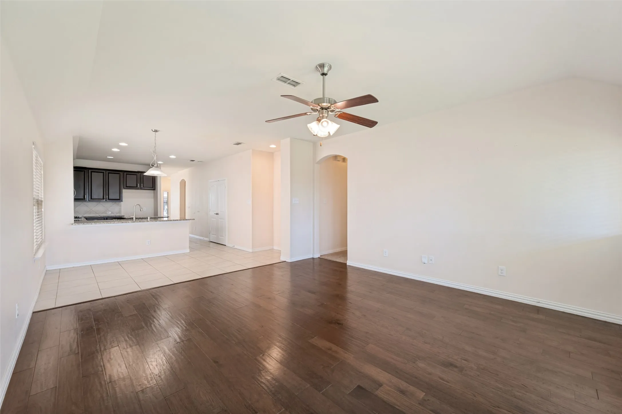 Spacious common area featuring wood-finish flooring, a ceiling fan with integrated lighting, and vaulted ceilings