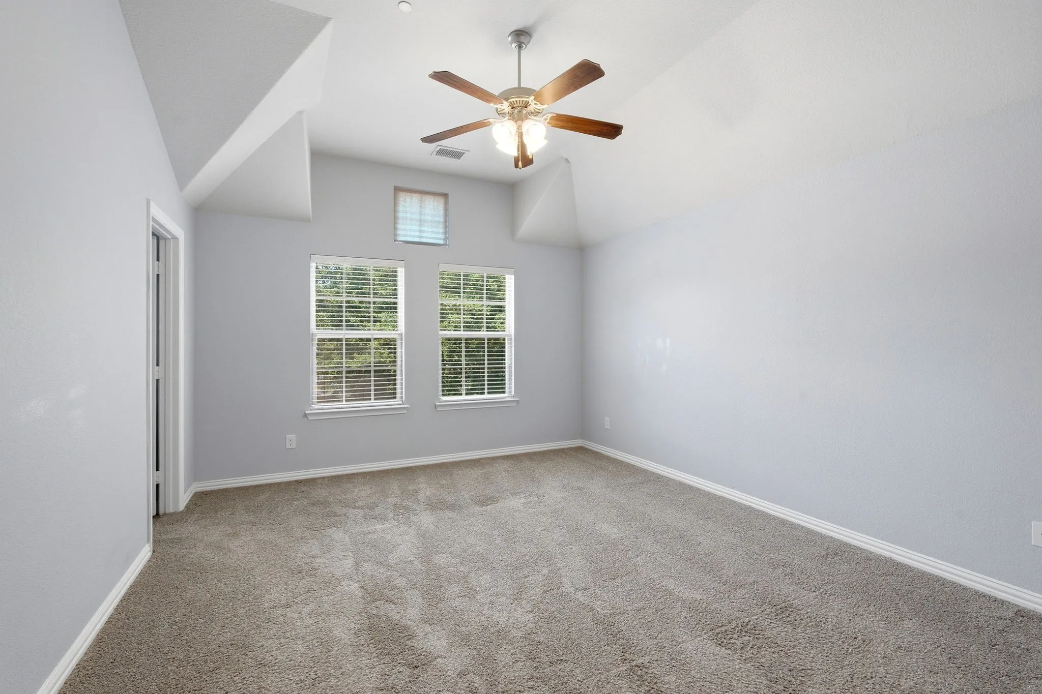 Primary bedroom with raised ceiling and ceiling fan adjacent to the en suite bathroom.