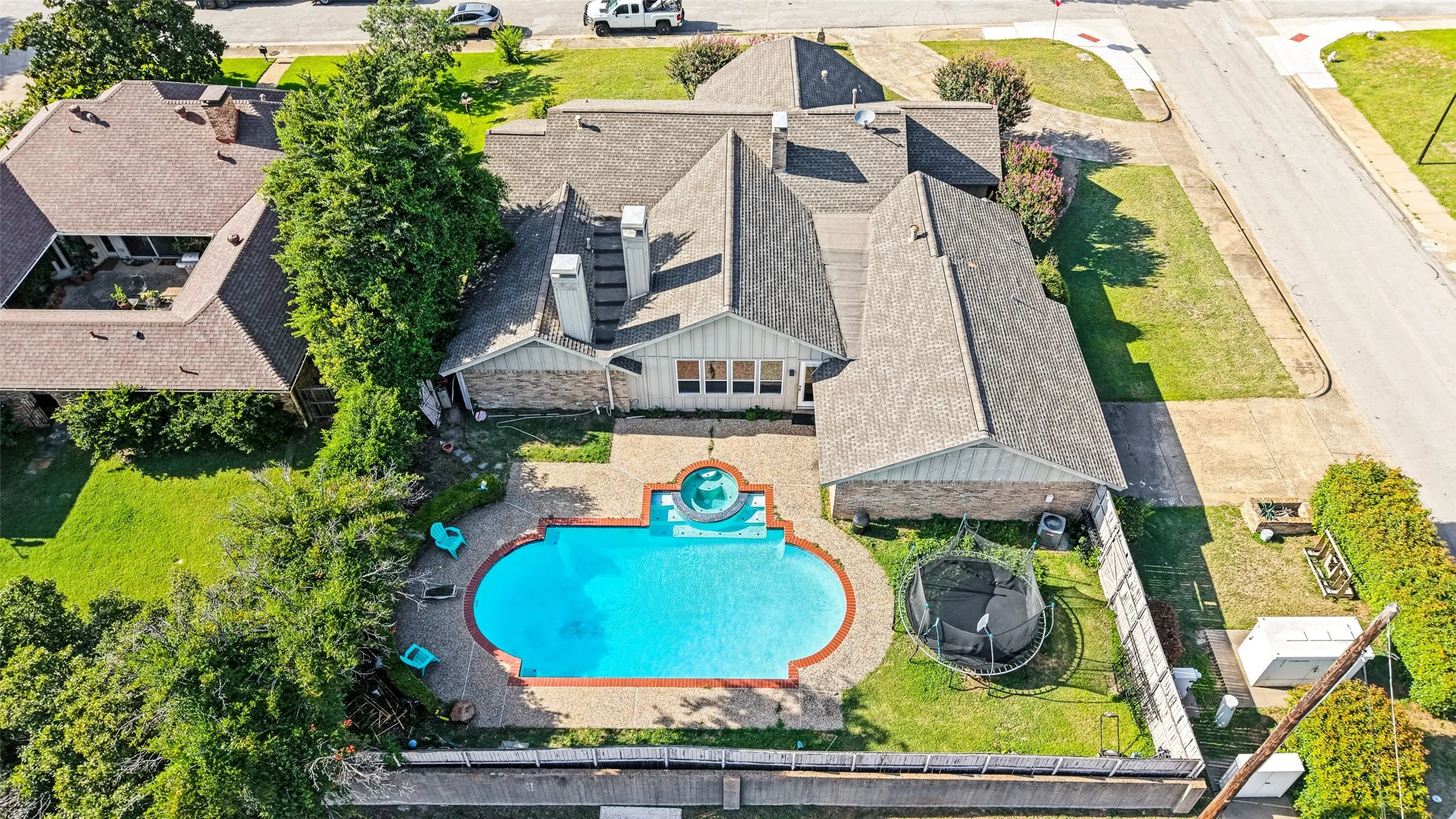 Resort-style backyard featuring a large swimming pool with a connected spa, surrounded by a brick paver deck