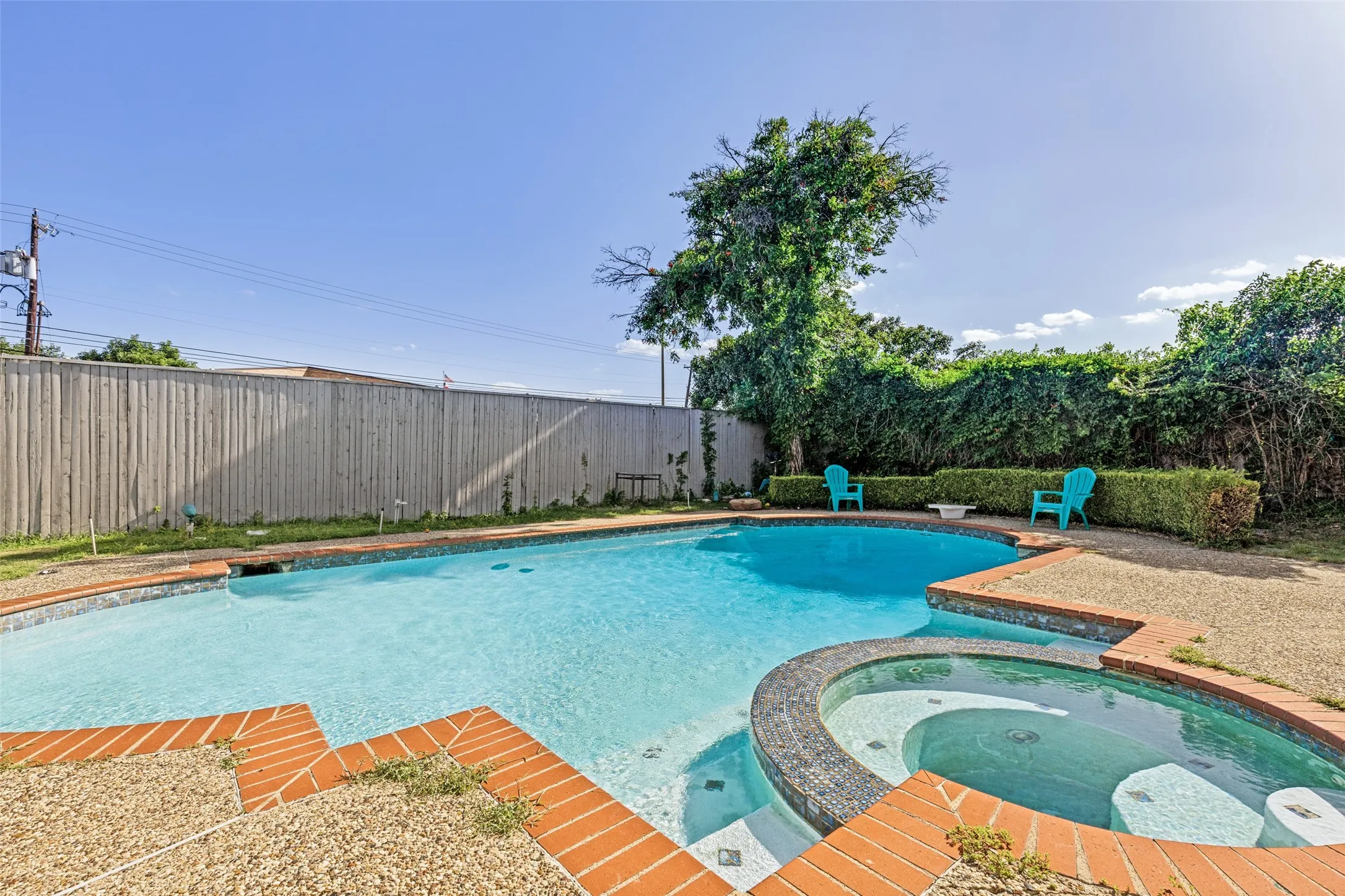 Inviting backyard featuring a sparkling swimming pool, integrated spa, brick coping, and a privacy fence