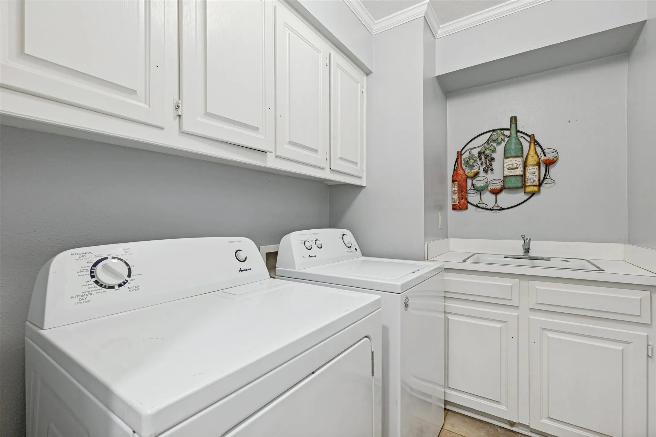 Laundry area featuring a utility sink, white cabinetry, and a countertop