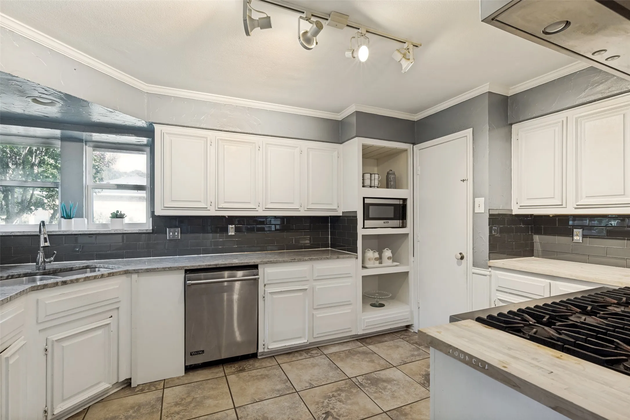 Kitchen featuring white cabinetry, a built-in microwave, stainless steel dishwasher, a gas cooktop, and a tile backsplash