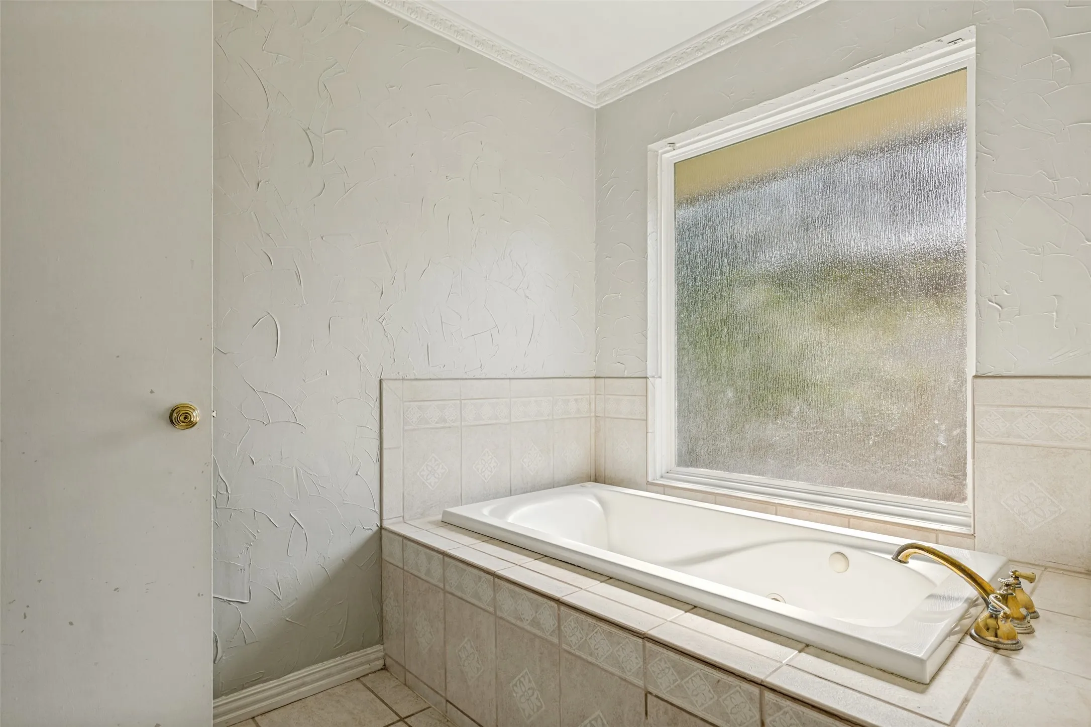 Built-in soaking tub with a tiled surround and brass fixtures