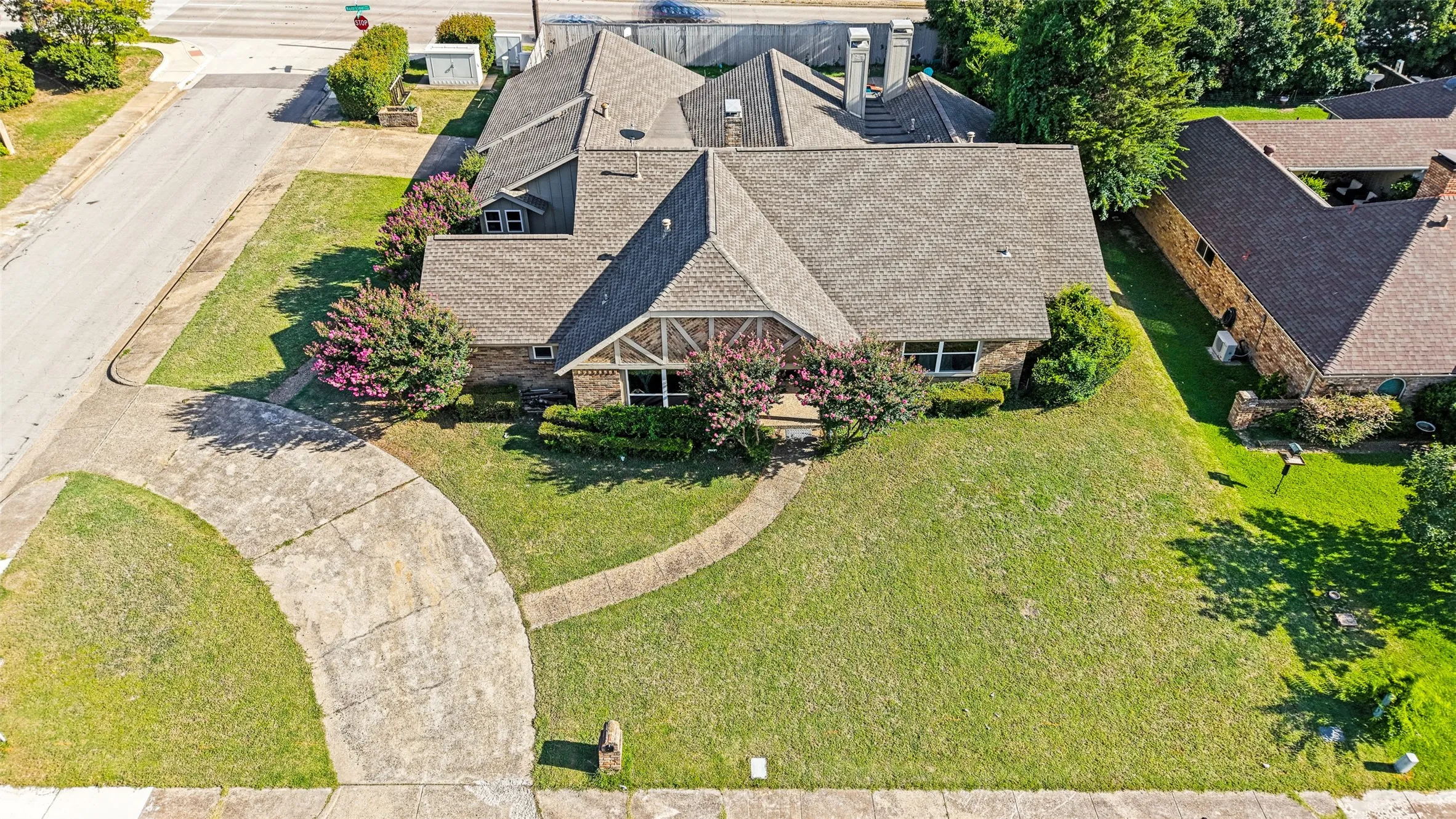 Expansive front yard featuring a curved concrete driveway, a separate stone walkway, and a manicured lawn