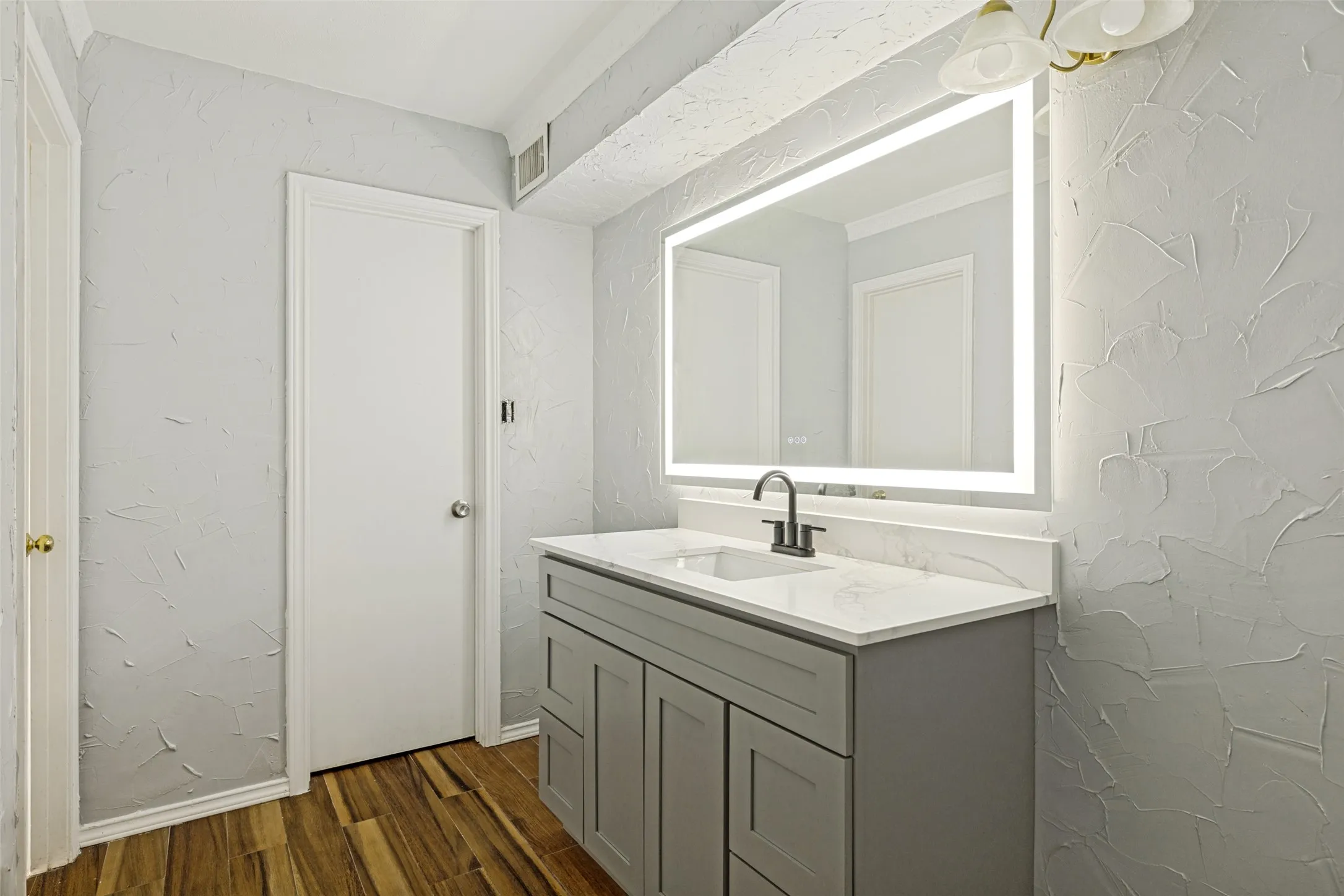 Bathroom vanity featuring a quartz countertop, integrated sink, and matte black faucet