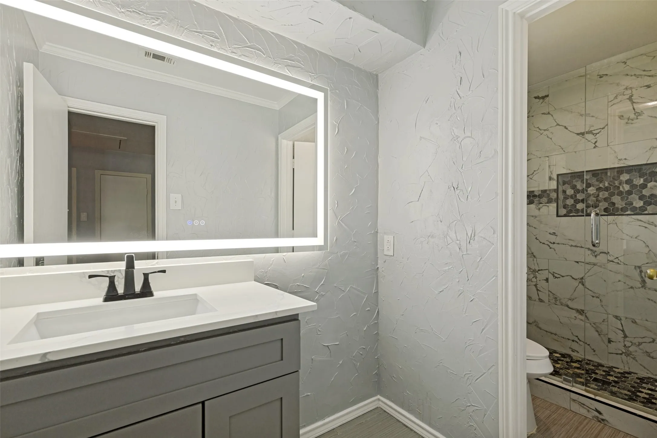 Bathroom vanity featuring a rectangular undermount sink, white countertop, and dark-finish faucet