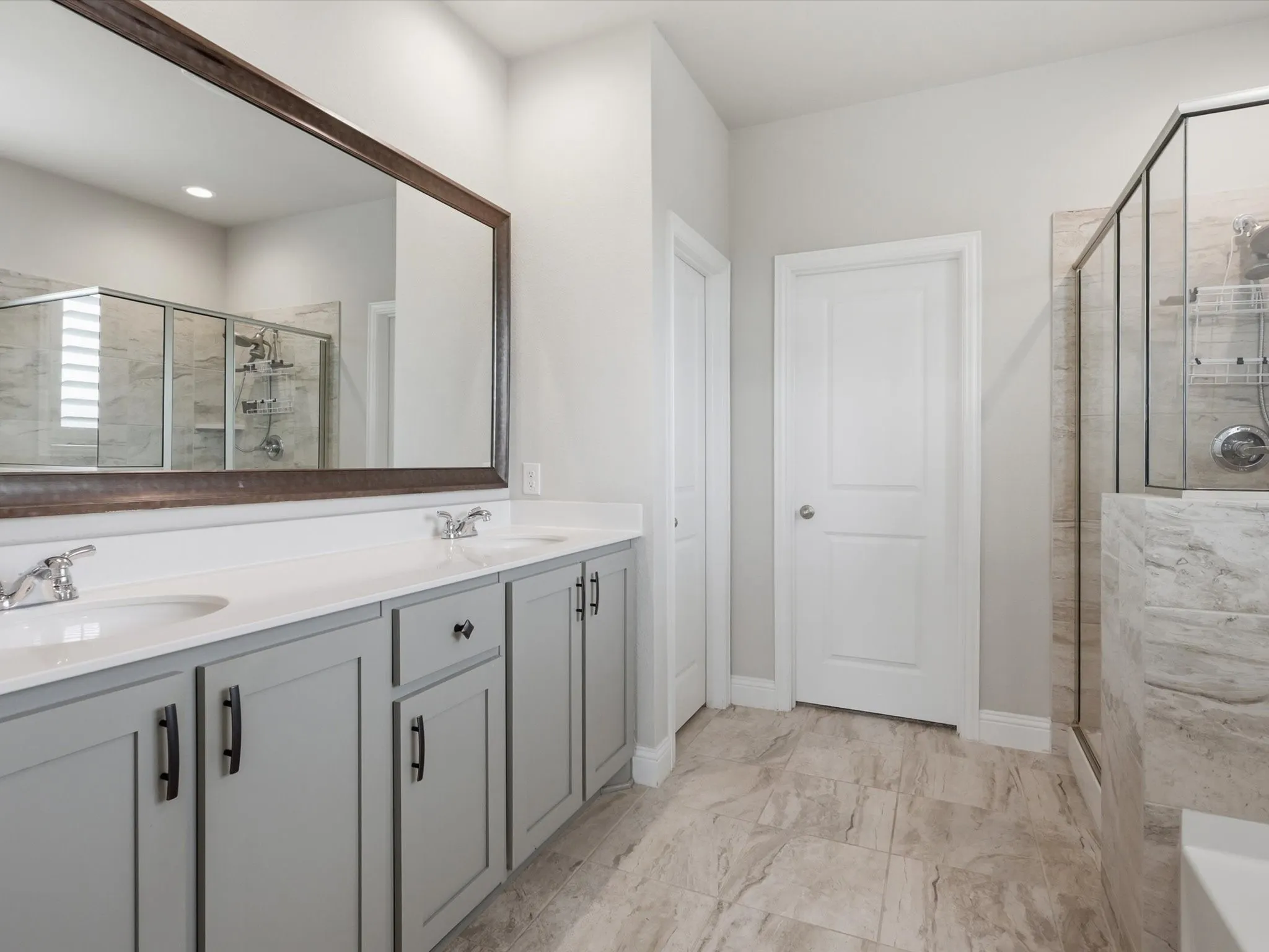 Dual vanity with light gray cabinetry and brushed nickel hardware, white countertops, and undermount sinks