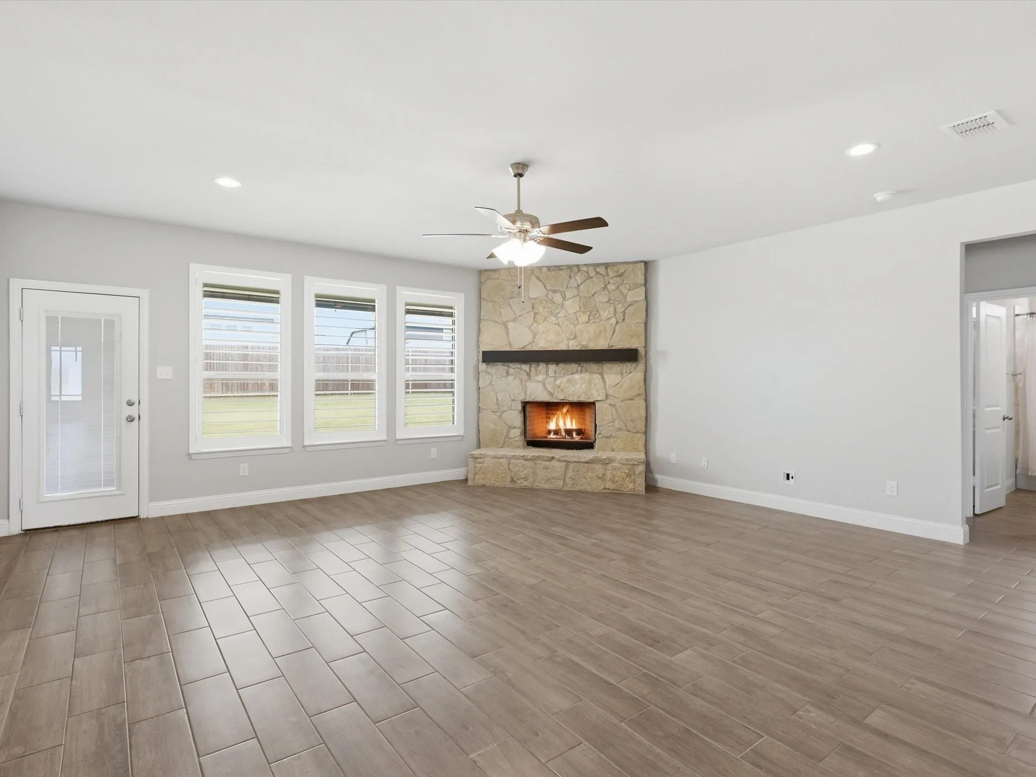 Spacious interior featuring wood-finish flooring and a stone-clad fireplace with a dark wood mantel