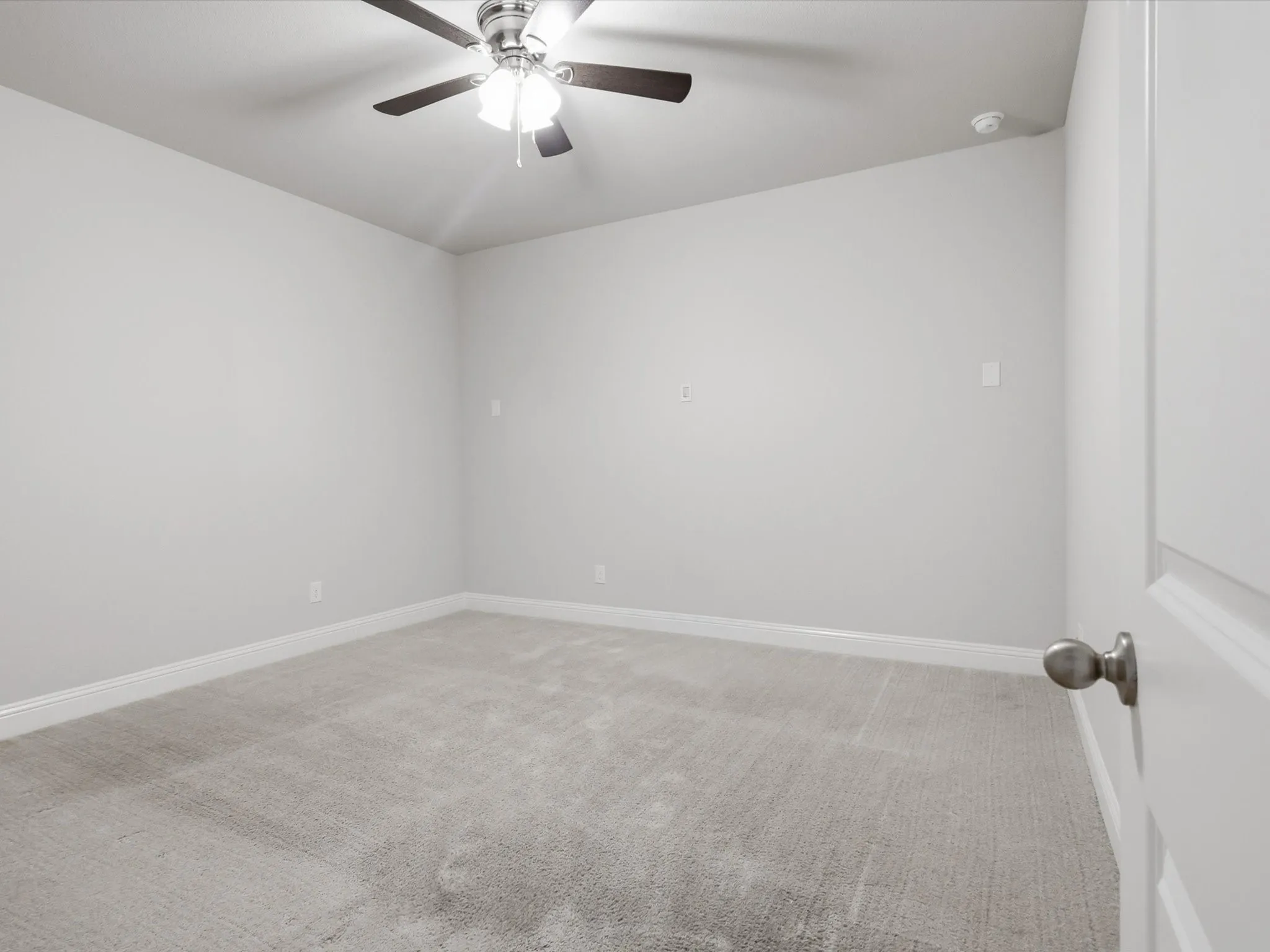 Neutral-toned room featuring a ceiling fan with integrated lighting, light gray wall paint, and gray carpet flooring