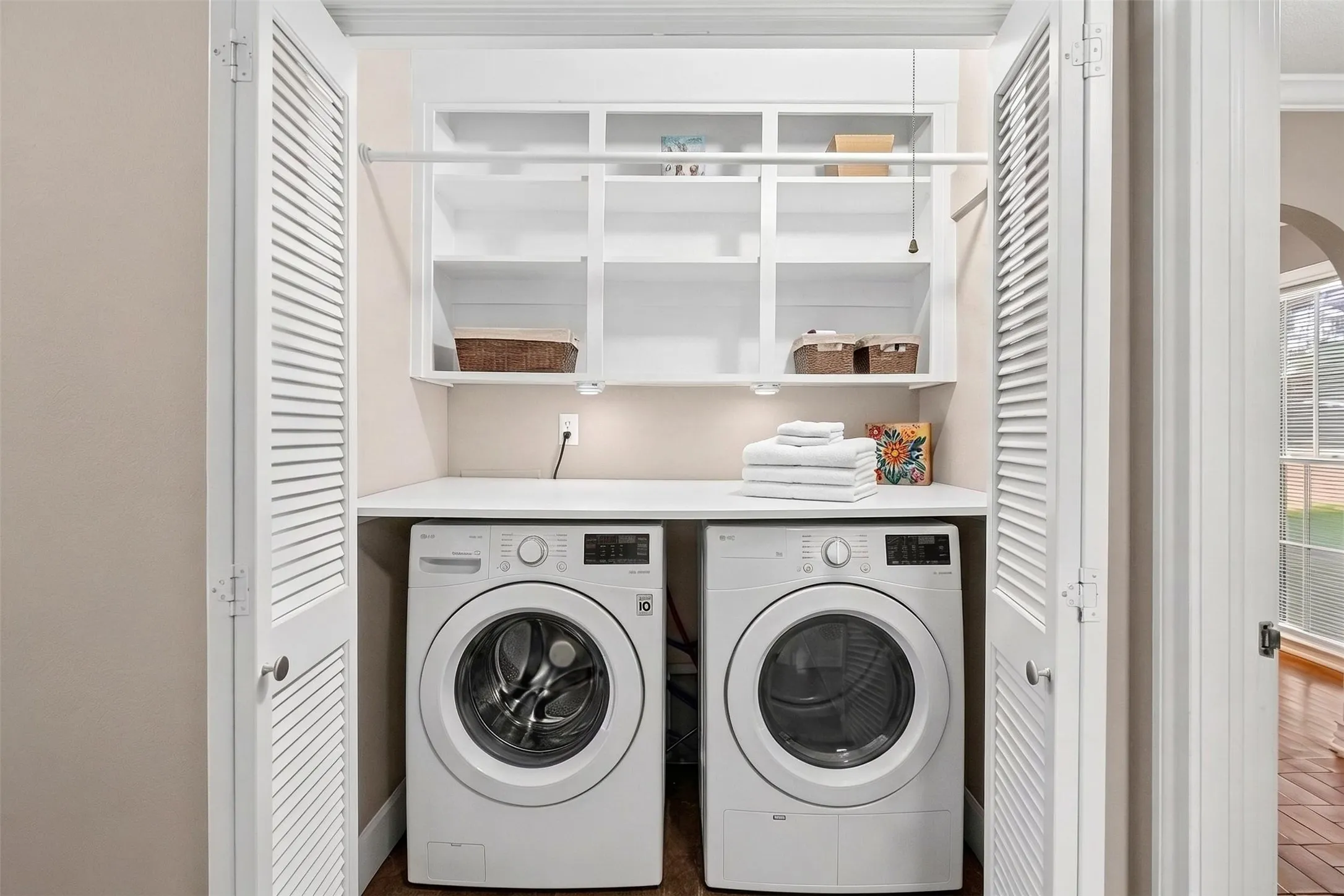 Virtually Staged: just a tidy, functional laundry space behind slatted doors. Lots of storage packed in with shelves, a hanging bar, and a folding shelf.
