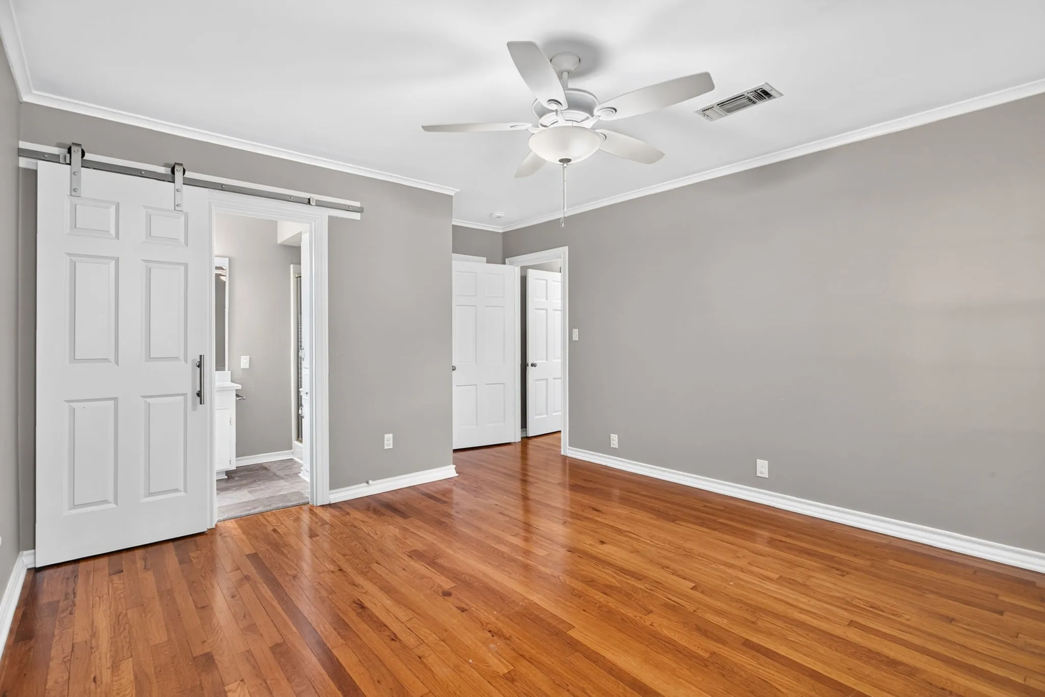 The sliding barn door helps conserve precious space for furniture. Ensuite bathroom beyond.