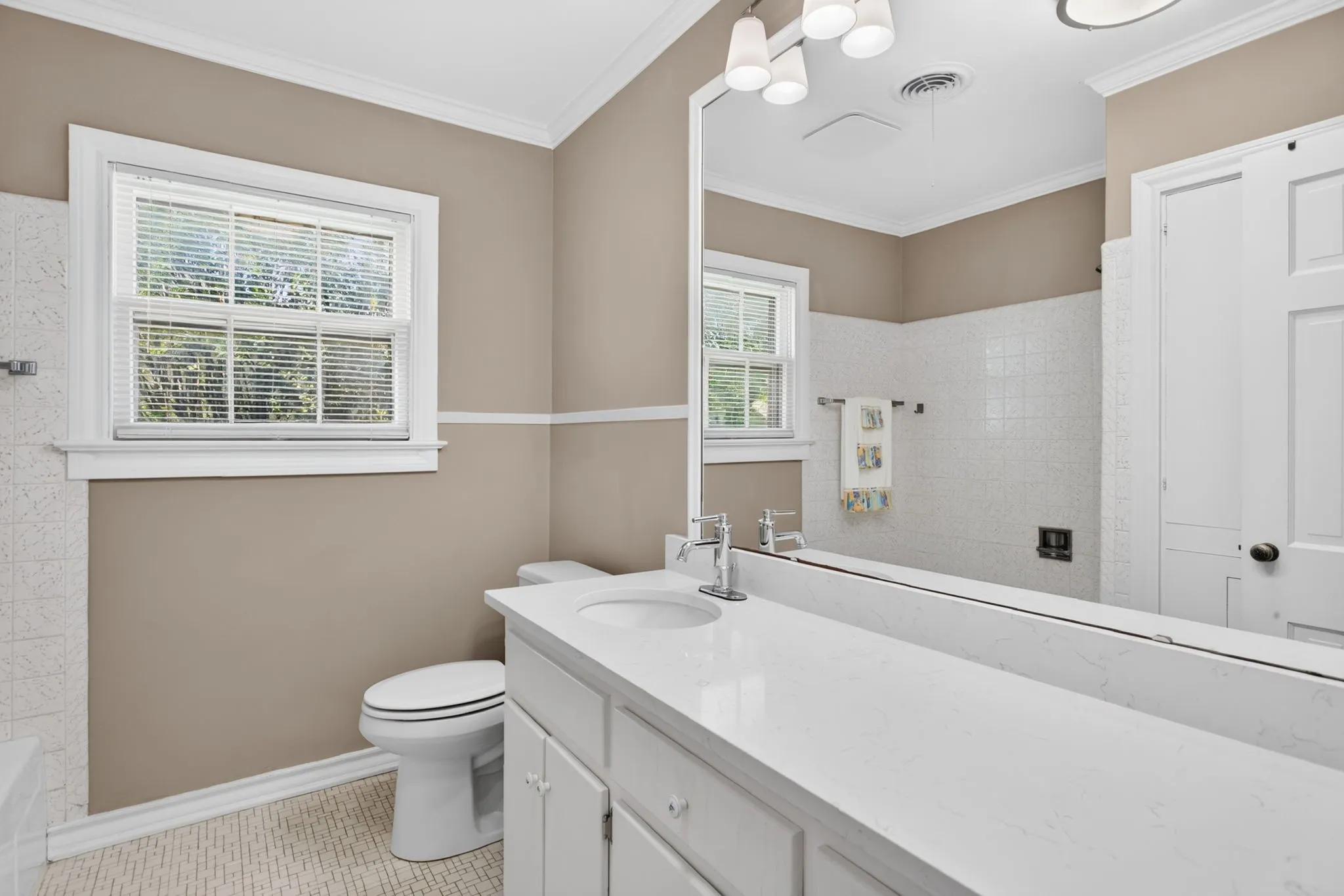 This full bathroom is precious and hardworking with the original tile details, new counter, sink and lighting - and the darling cabinet knobs.
