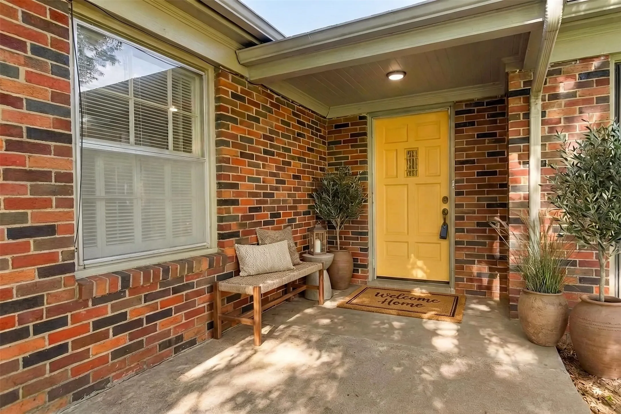Virtually Staged: sweet front porch with the ORIGINAL door and hardware painted in a sunny yellow. Original windows have solar screens.