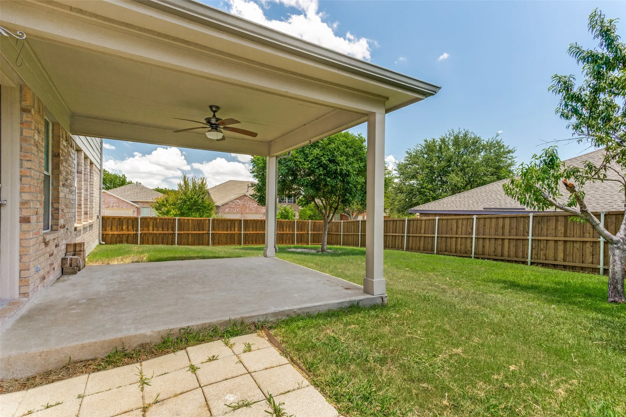 Covered patio featuring a ceiling fan, concrete flooring, and brick exterior