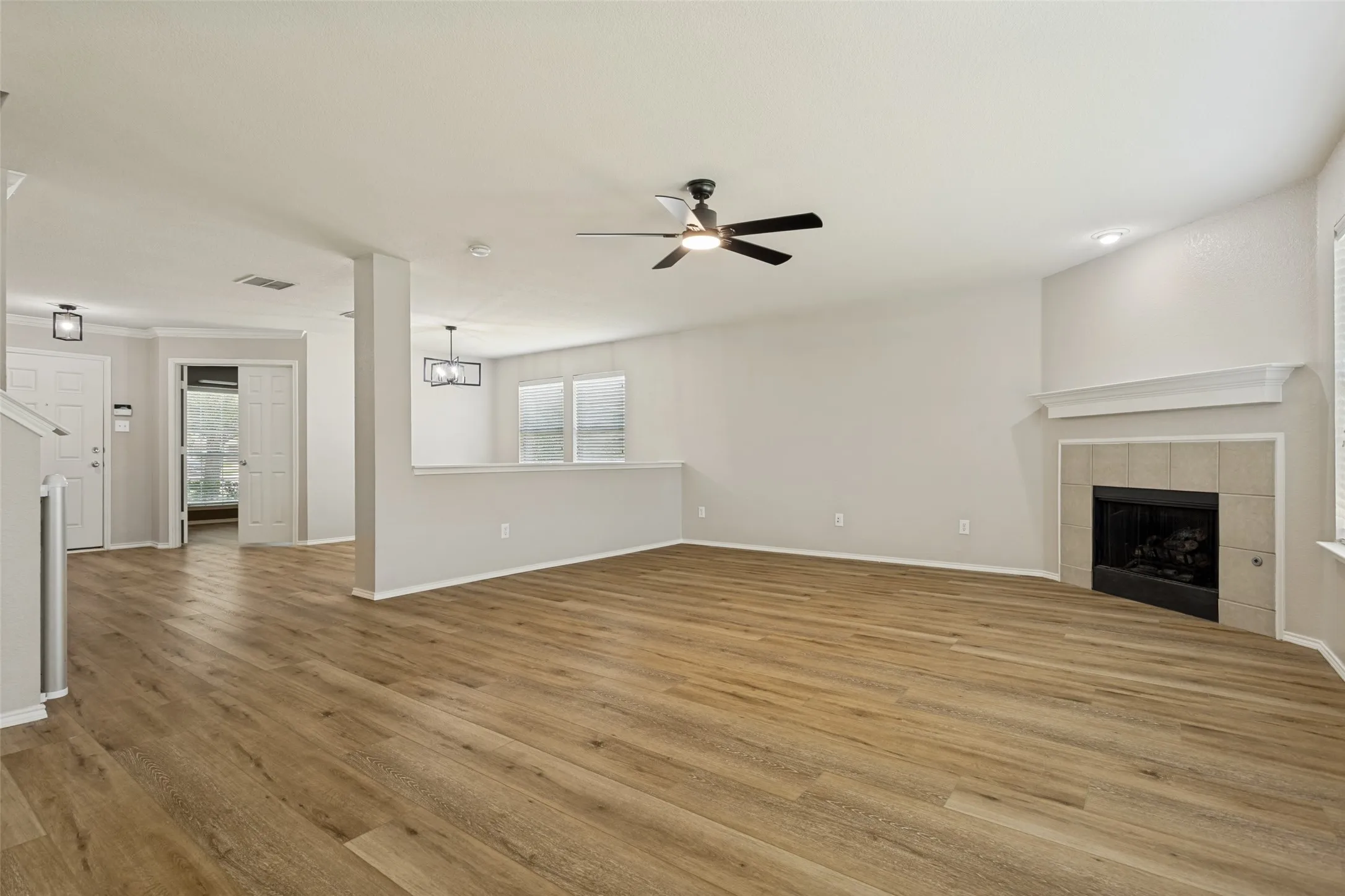 Spacious living area featuring wood-finish flooring and a tiled fireplace with a white mantel