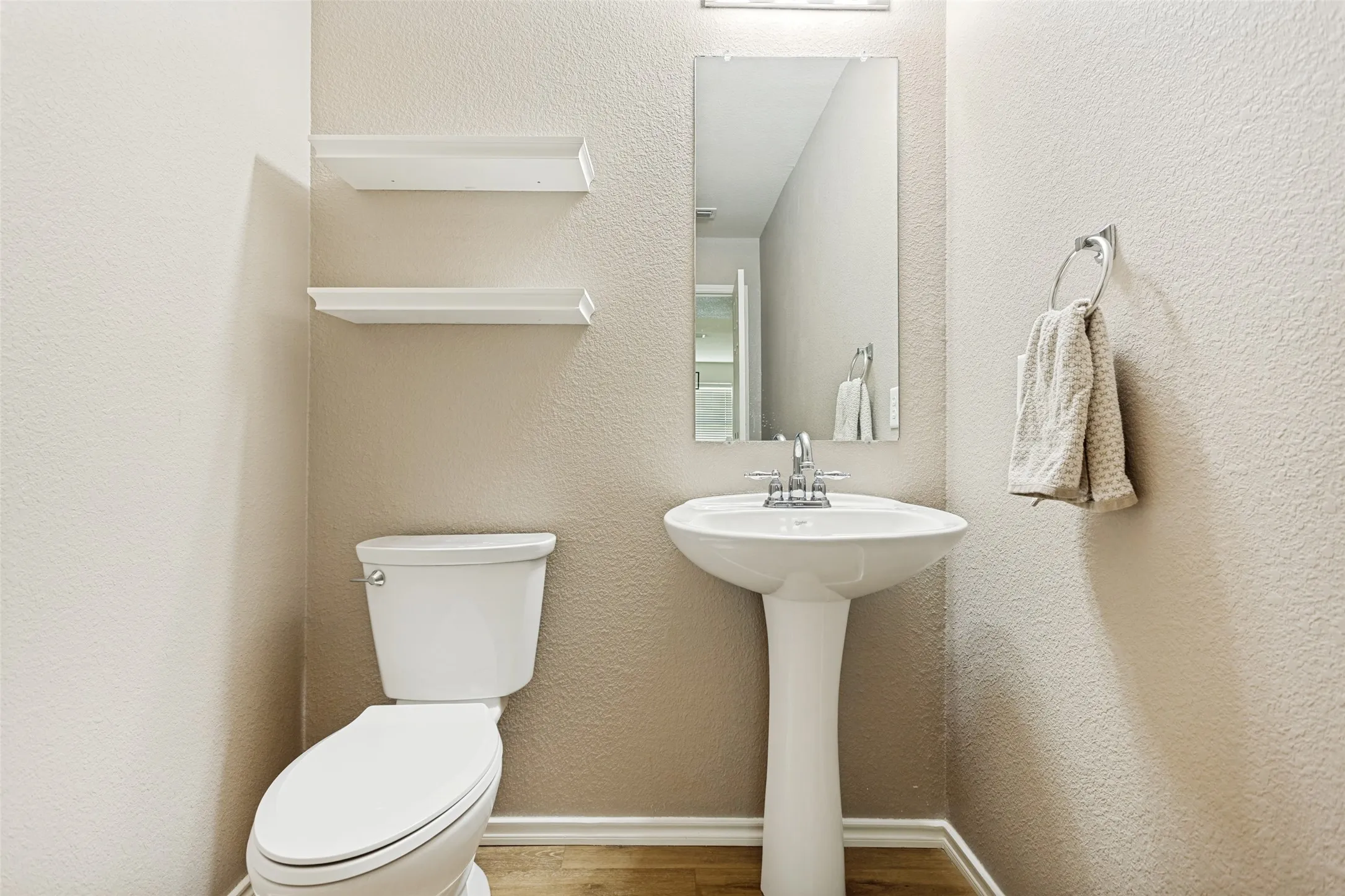 Pedestal sink featuring a chrome faucet, illuminated by an overhead light fixture