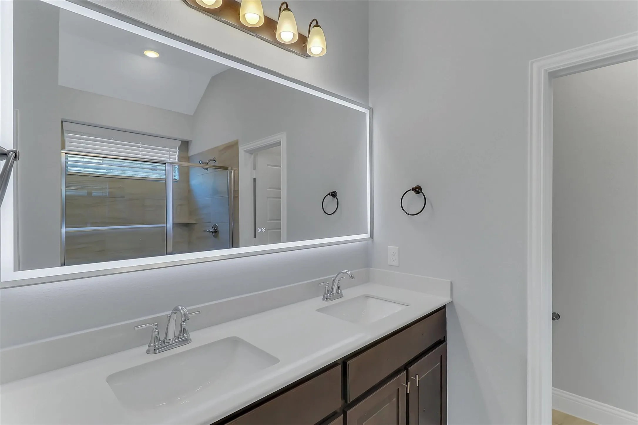 Dual vanity with integrated sinks, white countertops, dark wood-finish cabinetry, and chrome fixtures