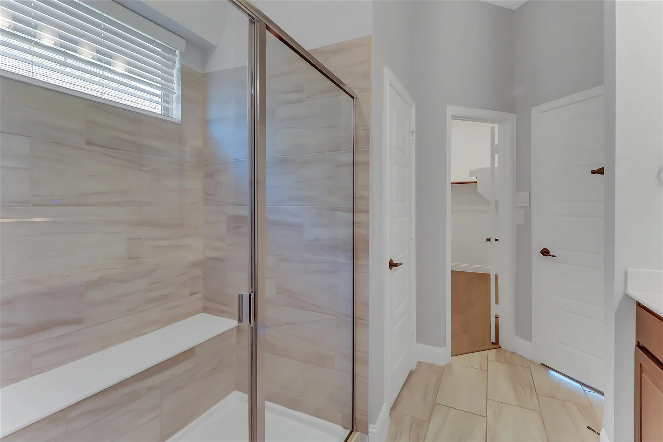 Walk-in shower with full-height tile surround, integrated bench, and clear glass enclosure