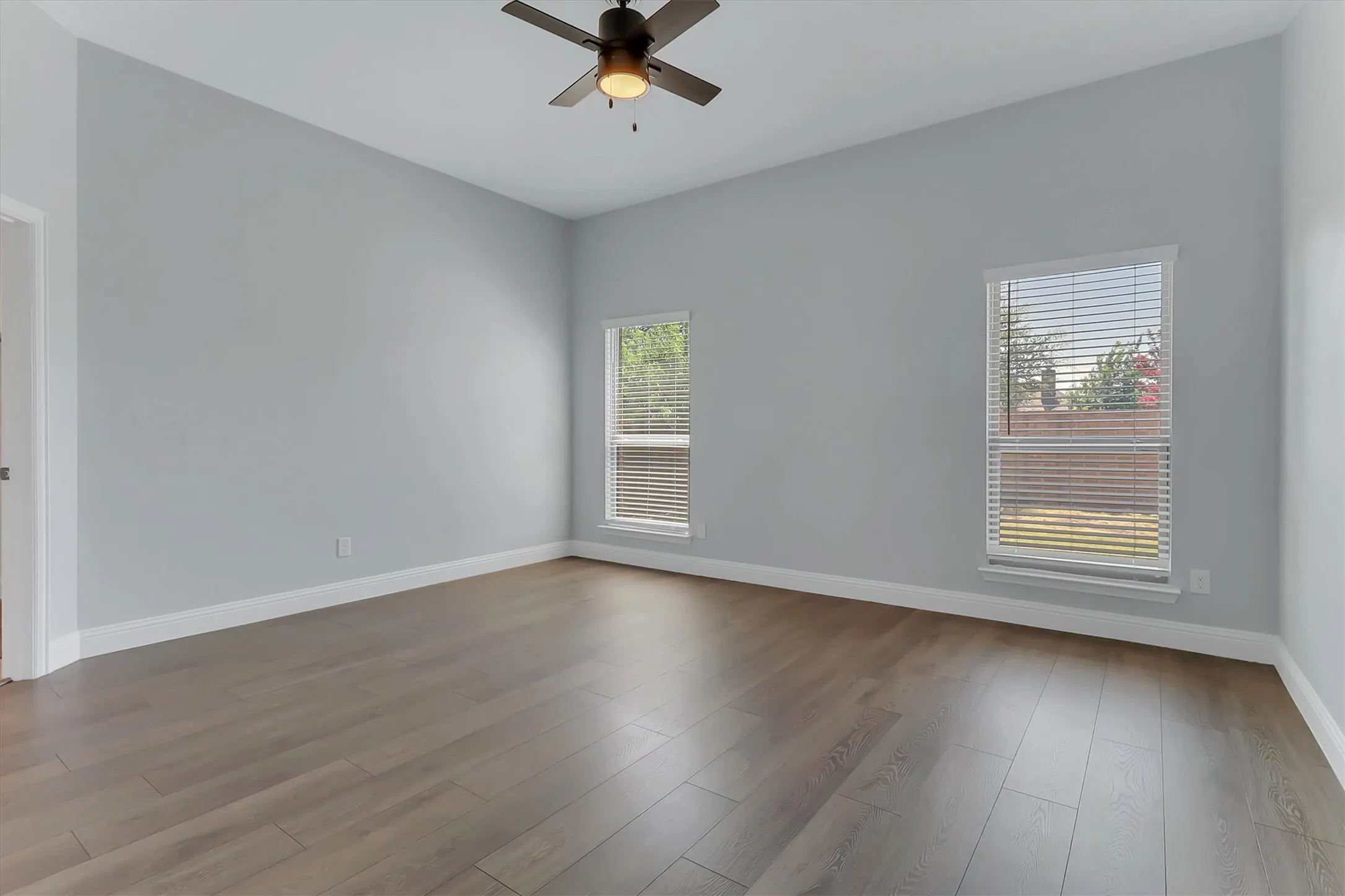Expansive room featuring contemporary gray walls and wood-finish flooring
